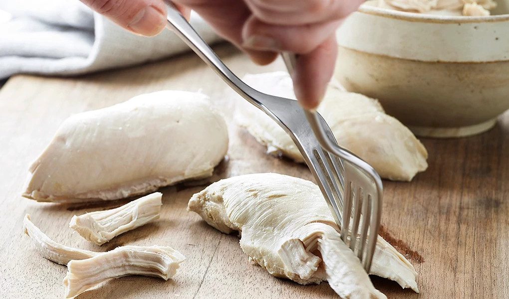 A close-up view of best poached chicken with forks in it