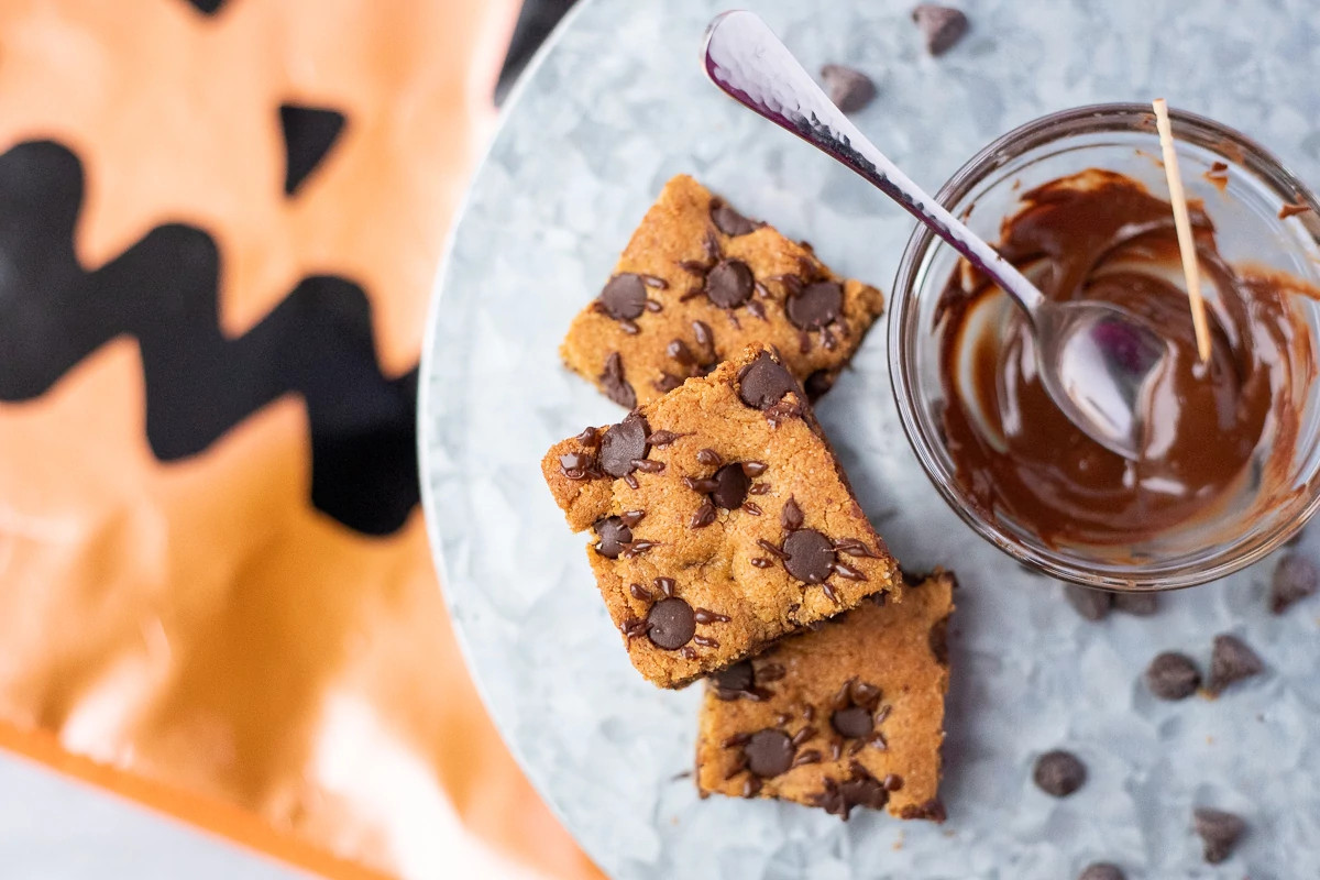 Gluten-free blondies next to a bowl of chocolate sauce