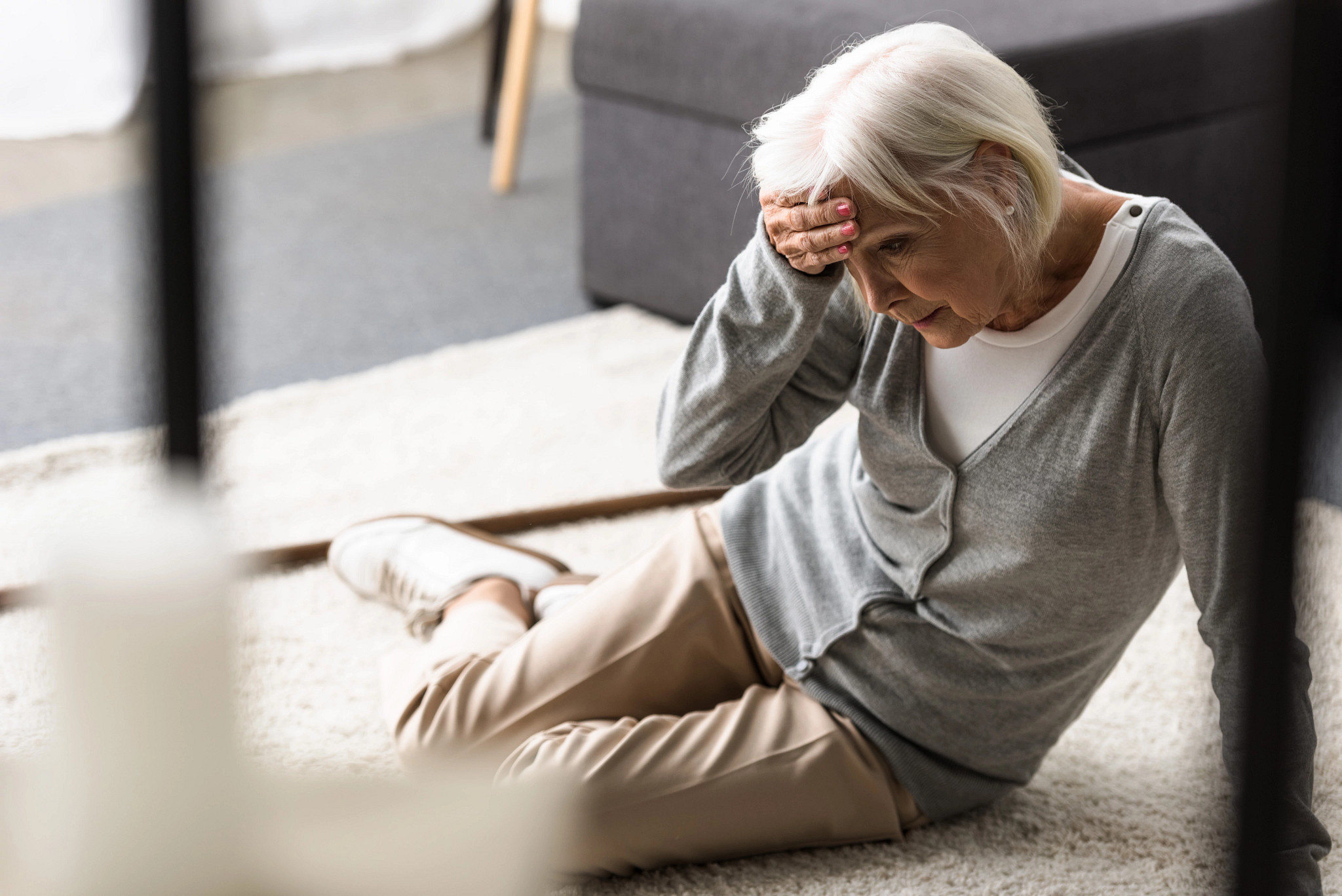 An older woman sitting on the floor after a fall, appearing distressed
