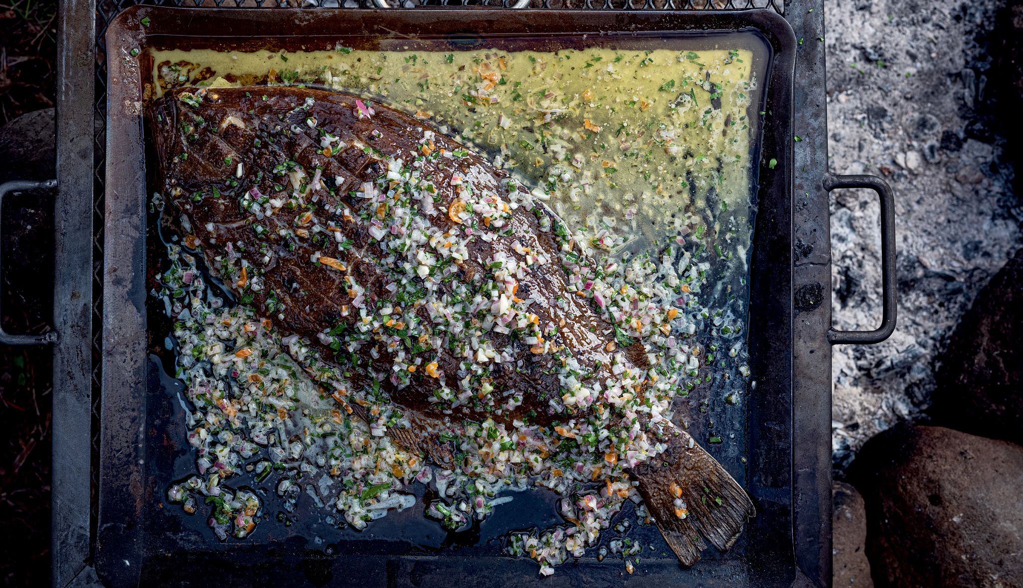 Grilled whole flounder with sauce chien beurre monté Flounder on baking dish with spices and sauce on it and around it