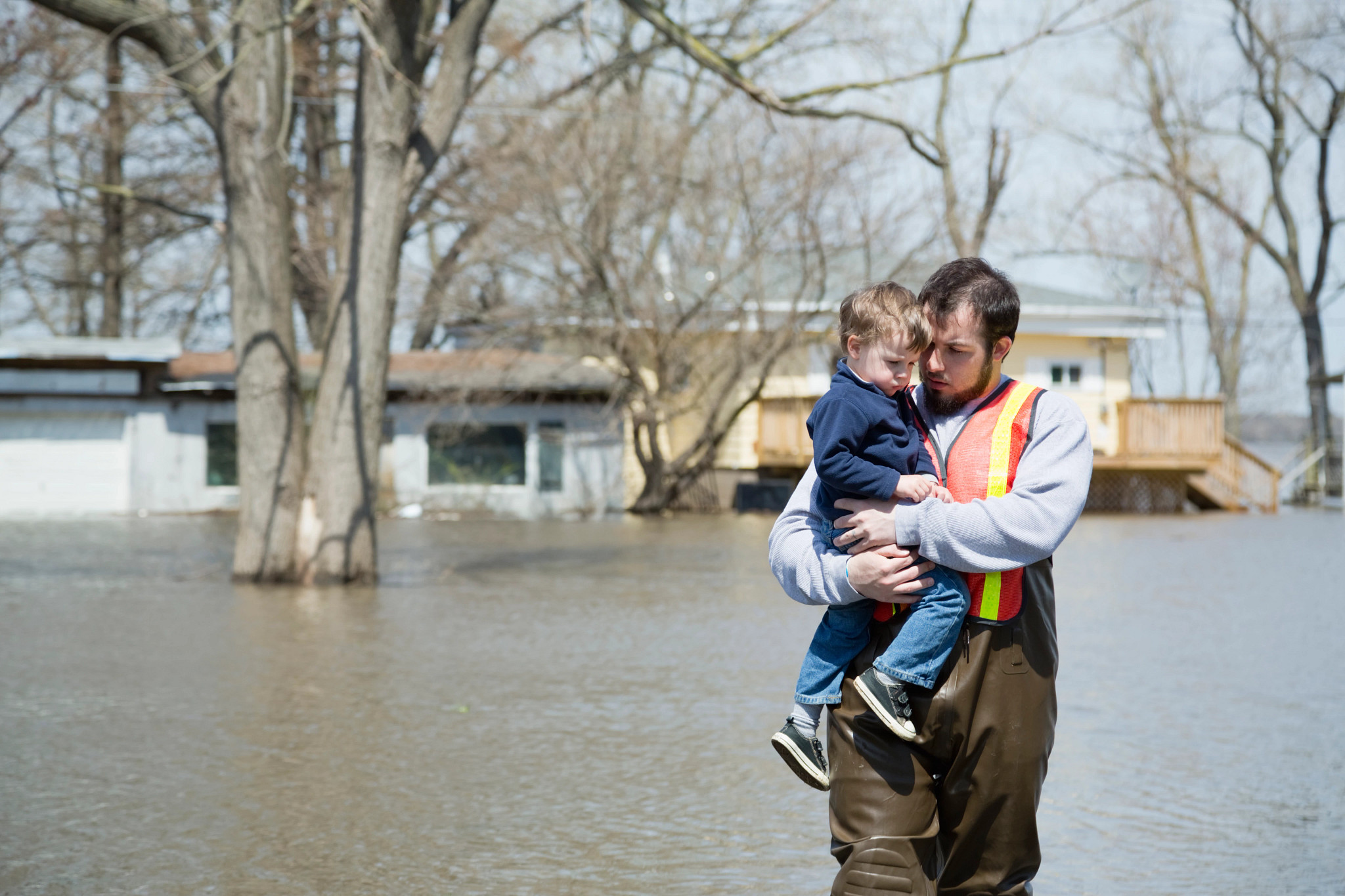 Man with son wading in floodwaters