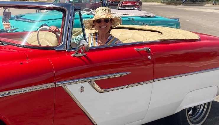 Camille Rae sentada en un automóvil rojo en La Habana
