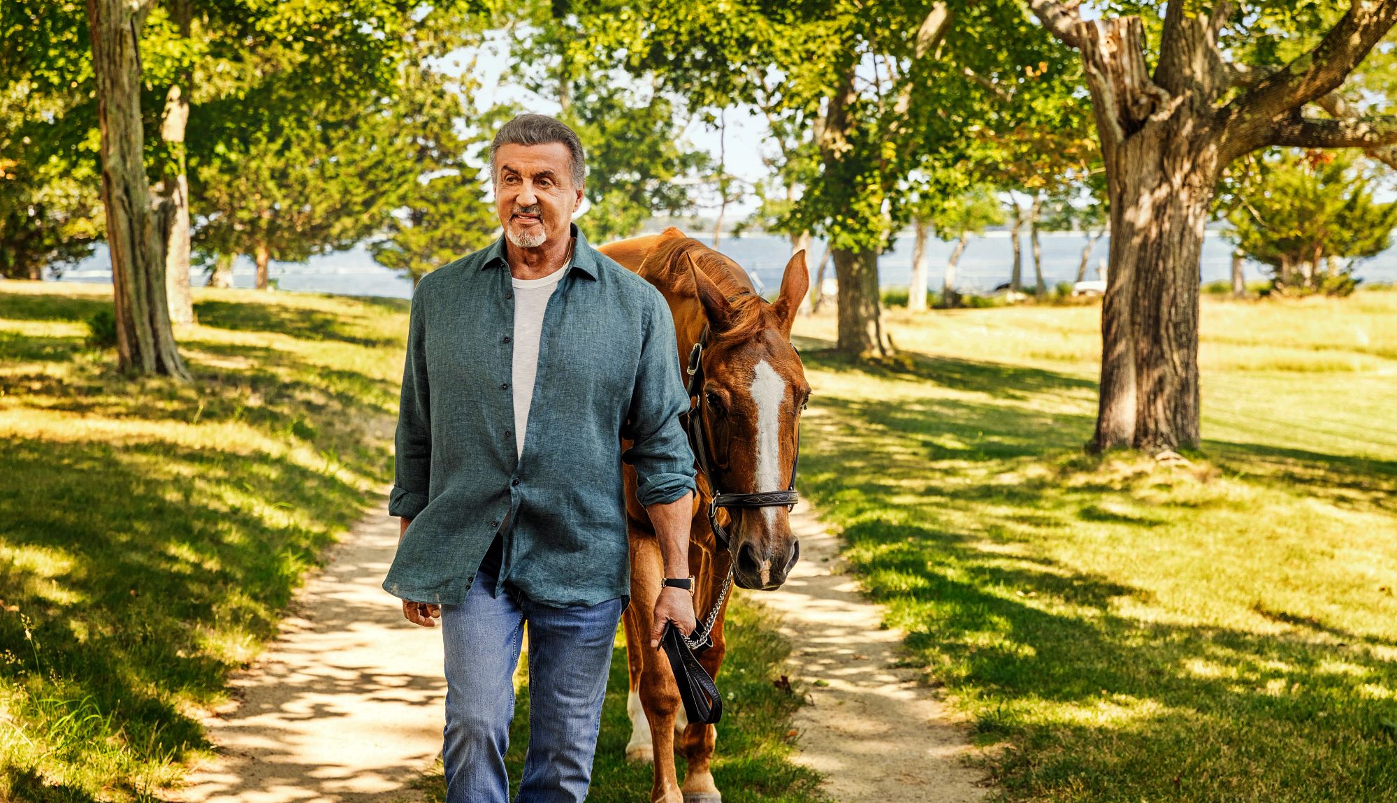 The Sylvester Stallone You Never Knew sylvester stallone leading a horse down a tree lined dirt road