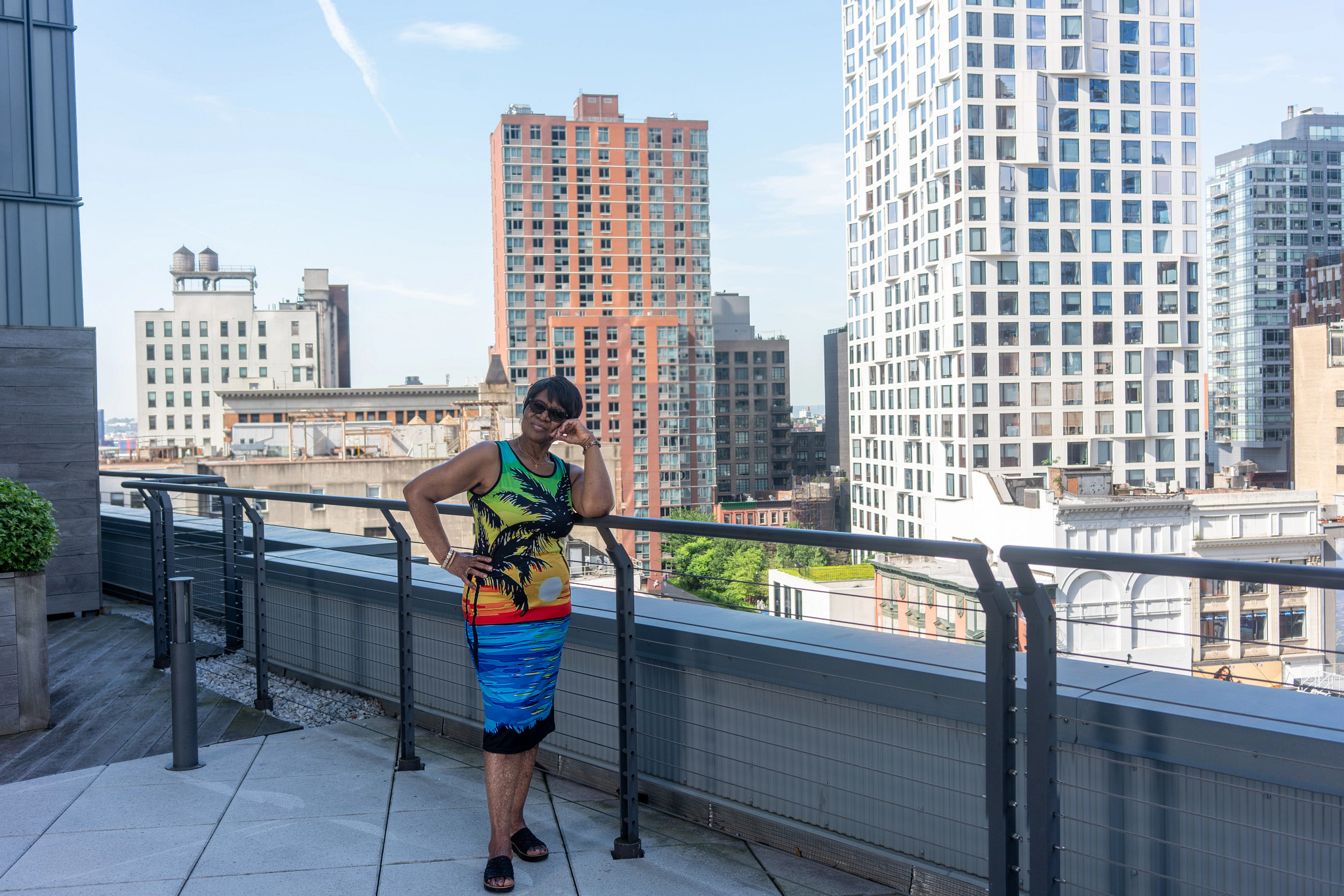 a woman in a bright dress stands on the roof of an apartment building