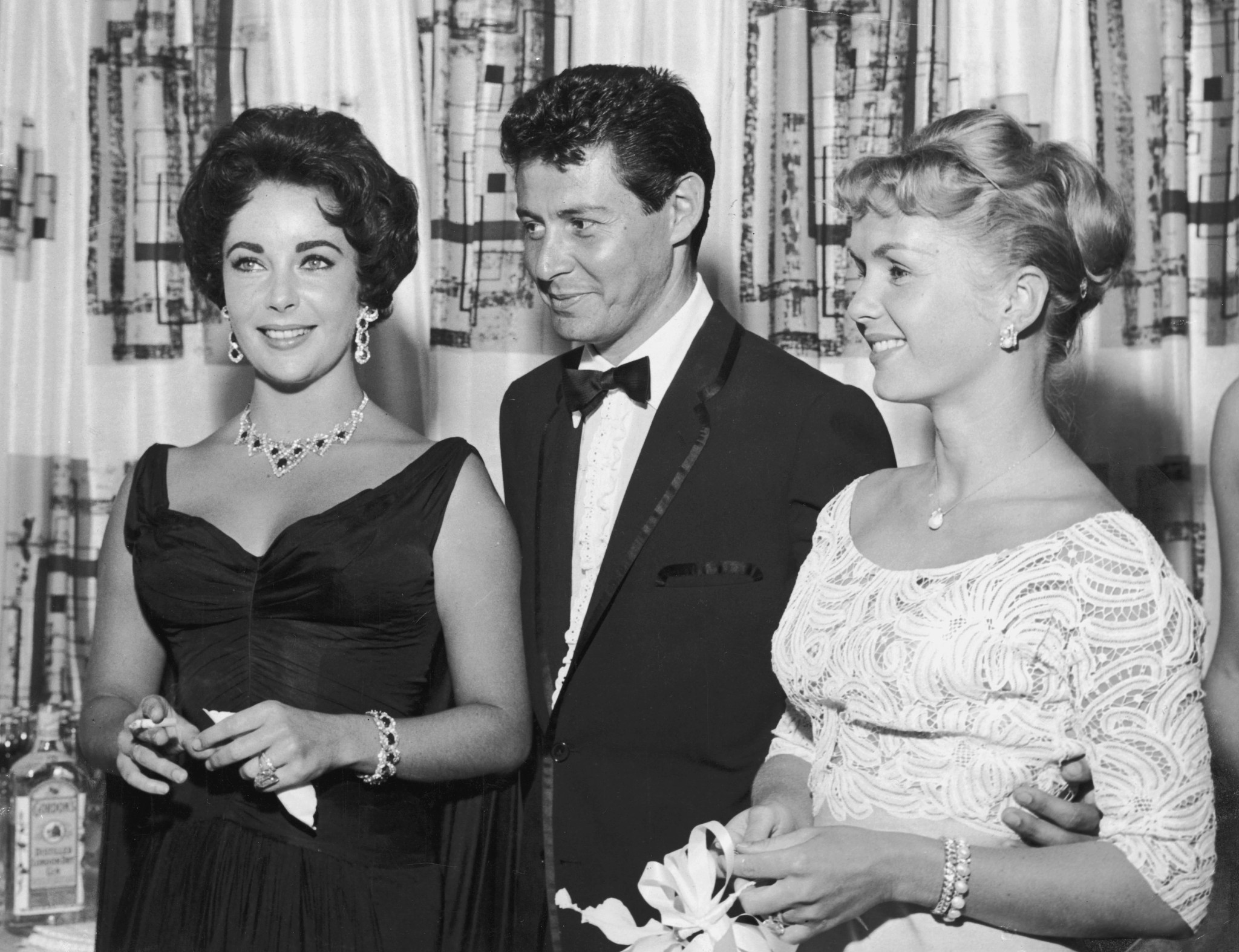 Elizabeth Taylor holding a cigarette standing alongside Eddie Fisher and Debbie Reynolds in Las Vegas