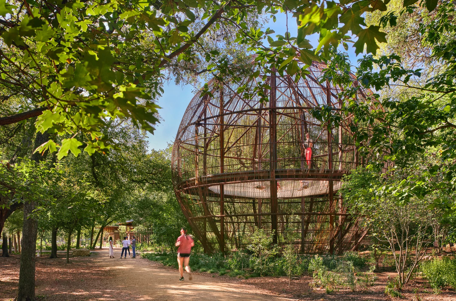 A path running along side a large globe structure known as the Pease Park Treehouse
