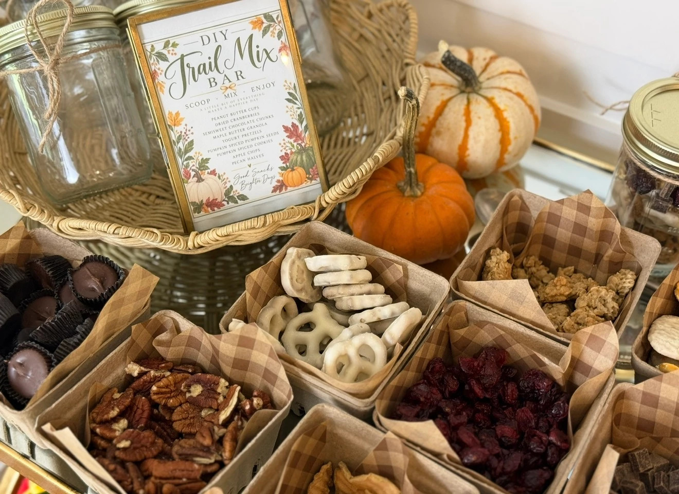 A DIY trail mix bar with baskets filled with granola, pecans, yogurt covered pretzels, dried cranberries and more