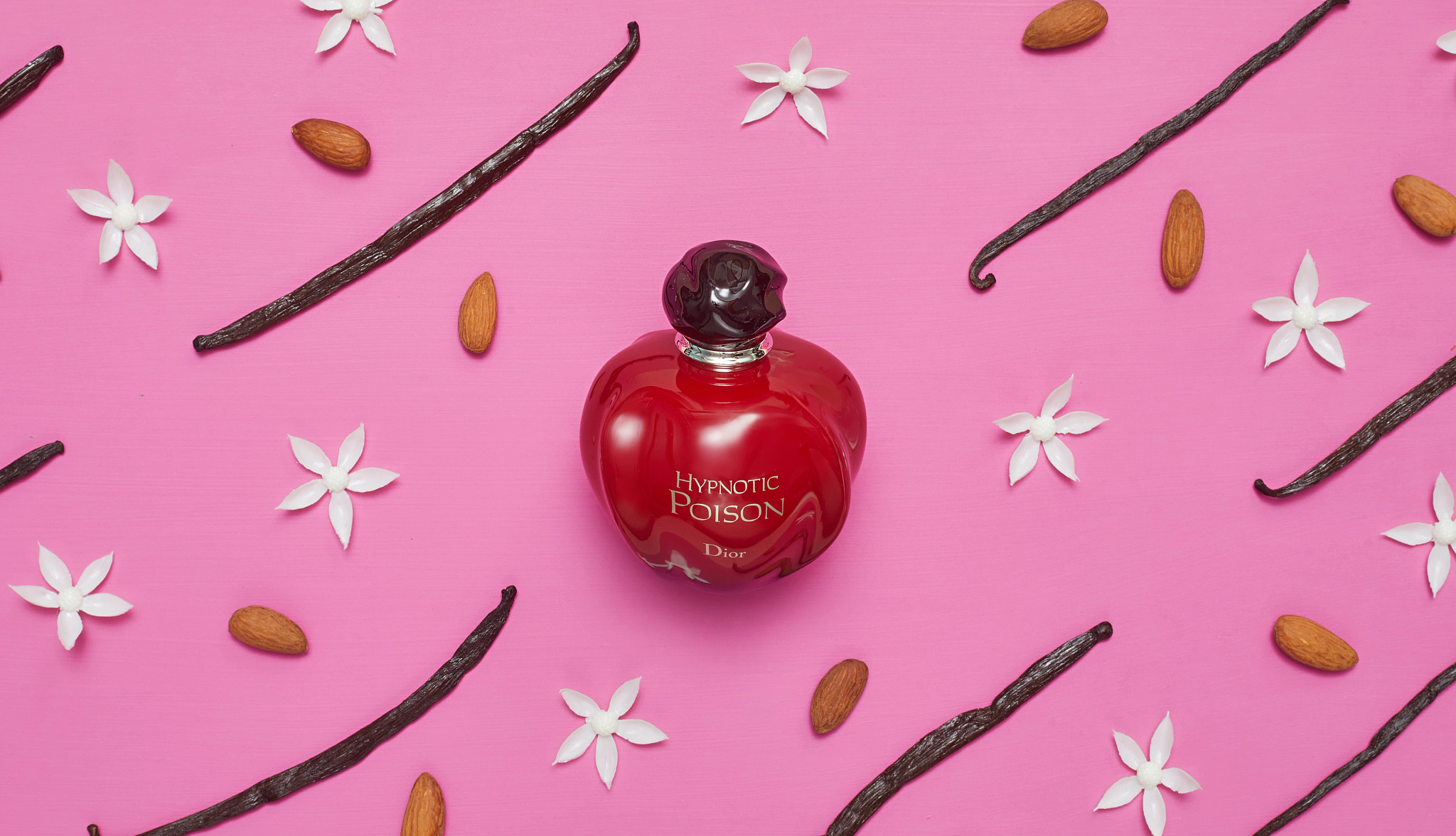 Bottle of Dior’s Hypnotic Poison surrounded by almonds, vanilla beans and jasmine flowers