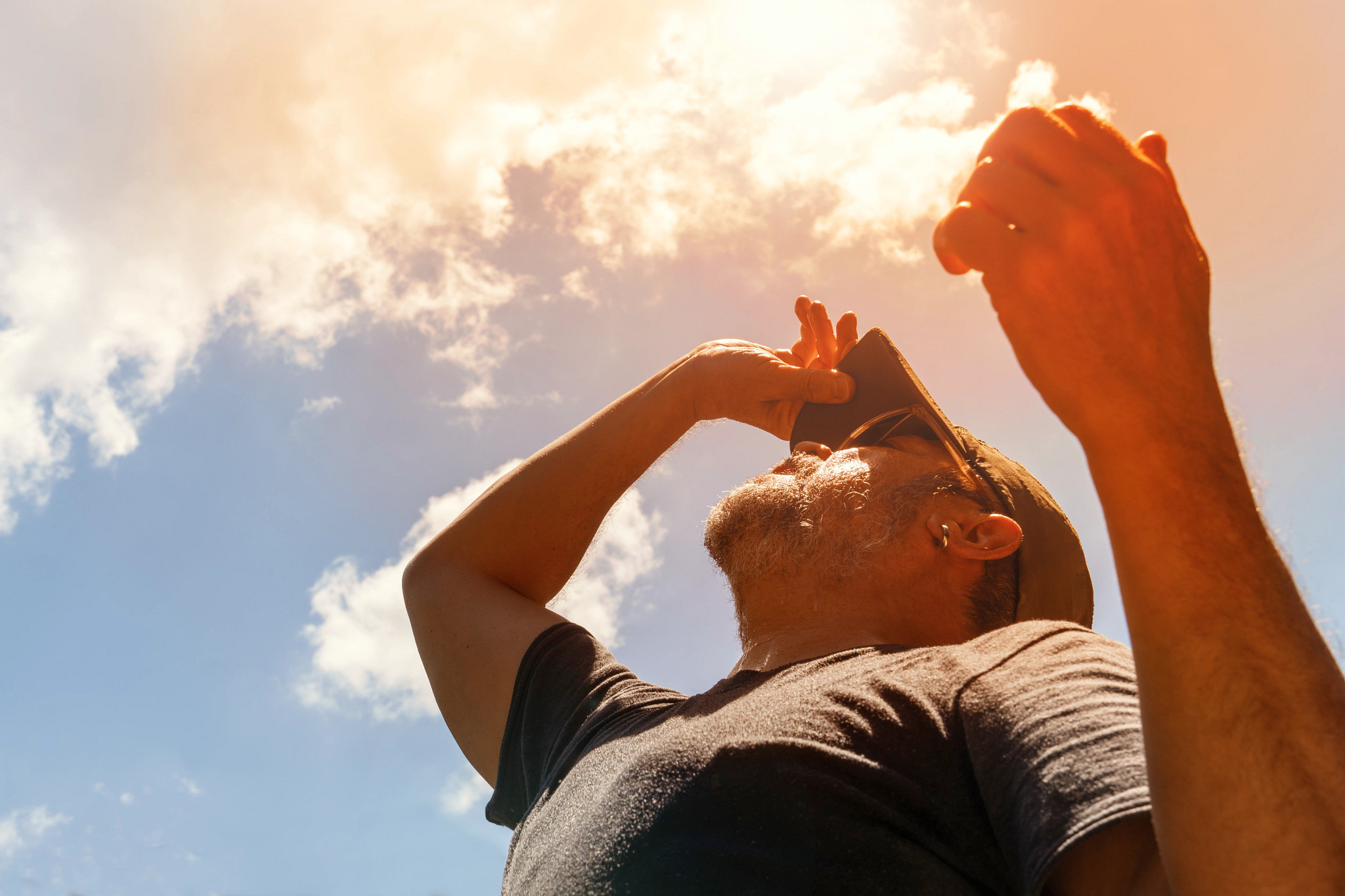 a man looking up at the sun denoting hot weather