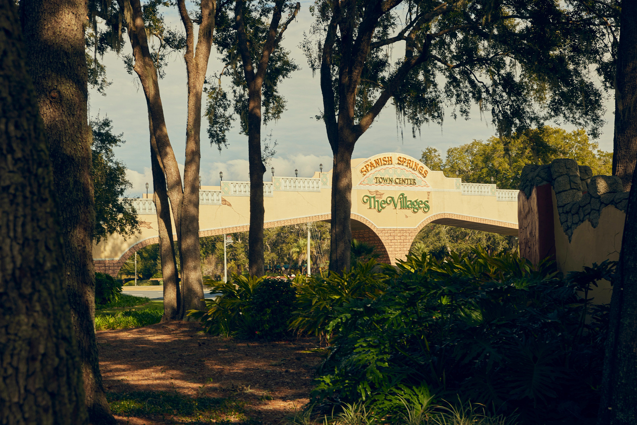 trees surround a sign saying spanish springs town center, the villages