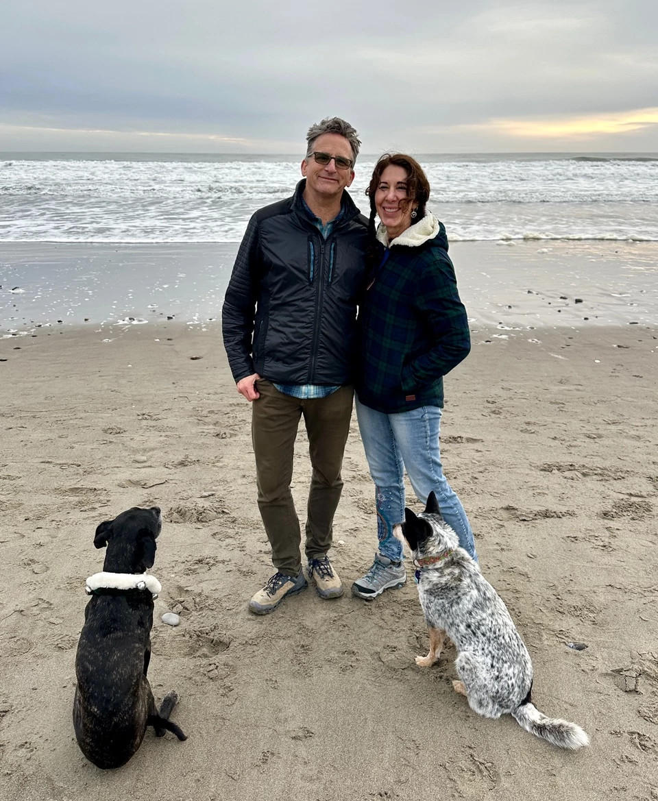 a photo shows Melanie Haiken and her fiancé walking their dogs on Stinson Beach in northern California.