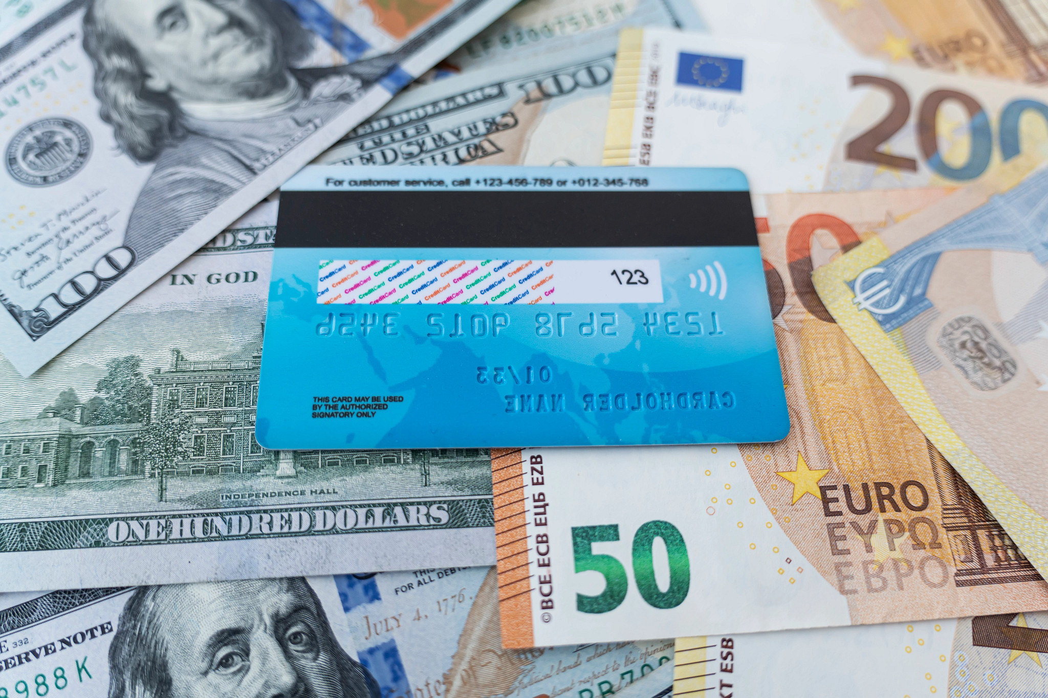 a credit card sits on top of various denominations of paper money