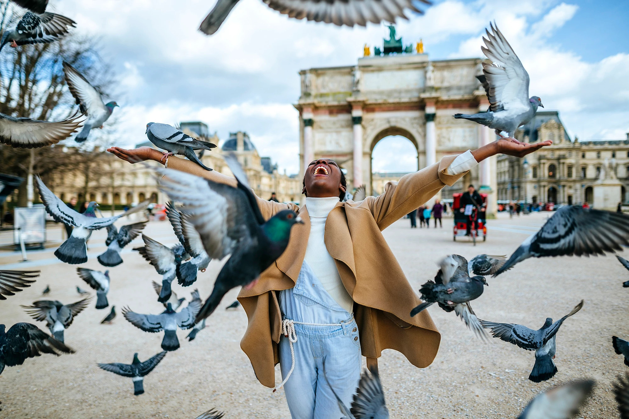 France, Paris, Happy young woman with flying pigeons at Arc de Triomphe