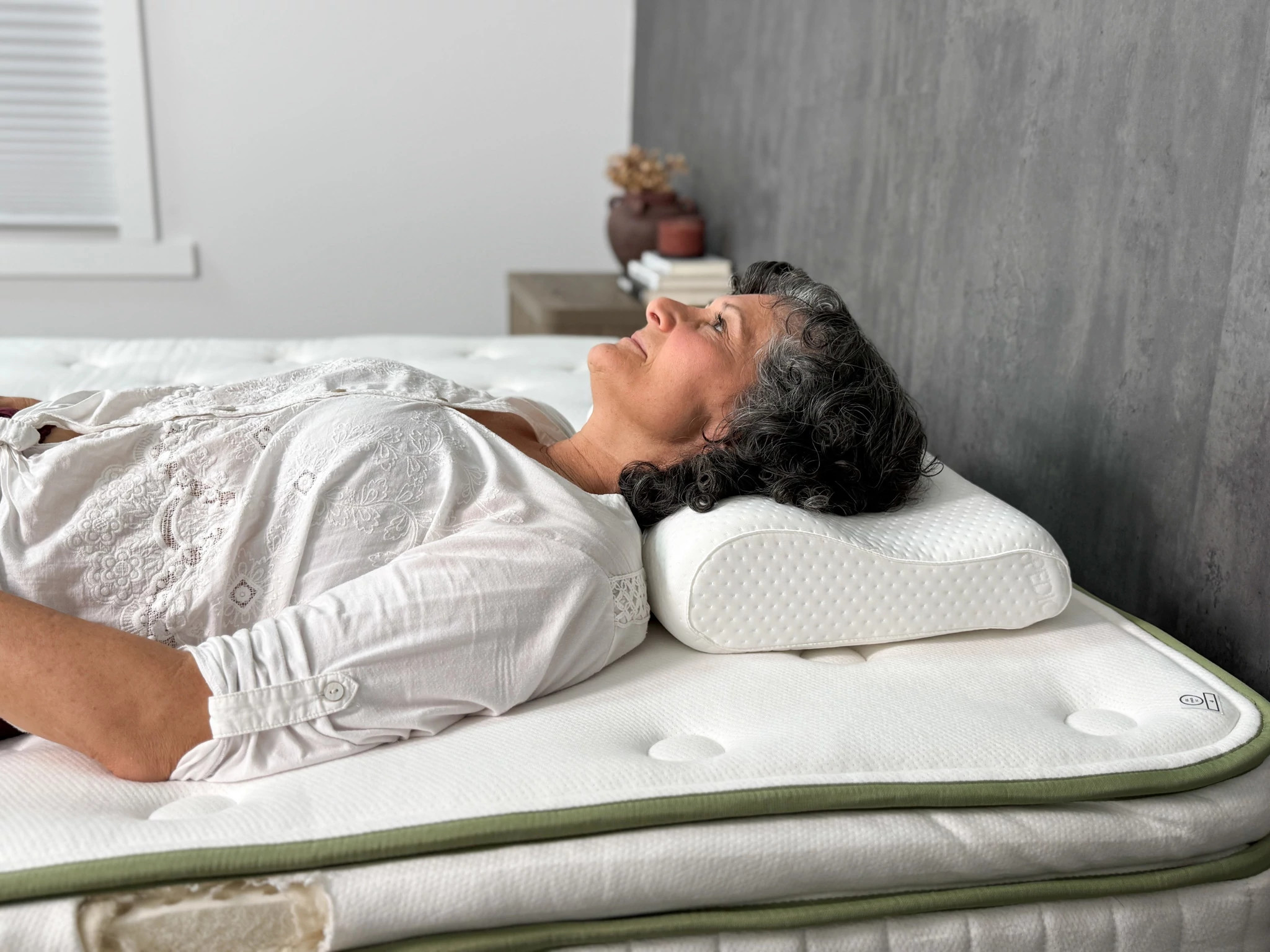 A woman back-sleeping on a mattress with her head resting on the Tempur-Pedic TEMPUR-Neck Pillow.