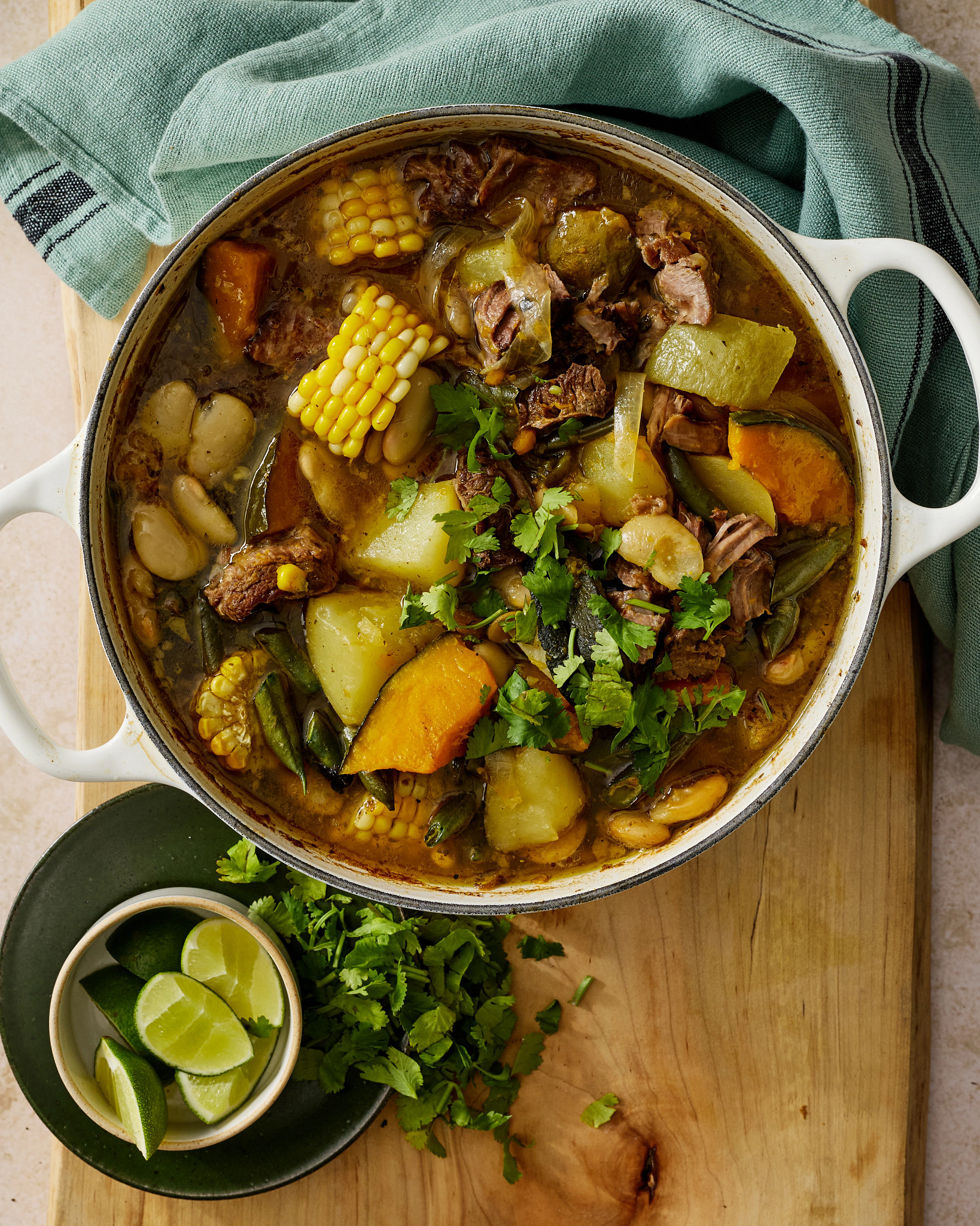 A photo shows puchero, a hearty Spanish stew, on a table being served from a dutch oven