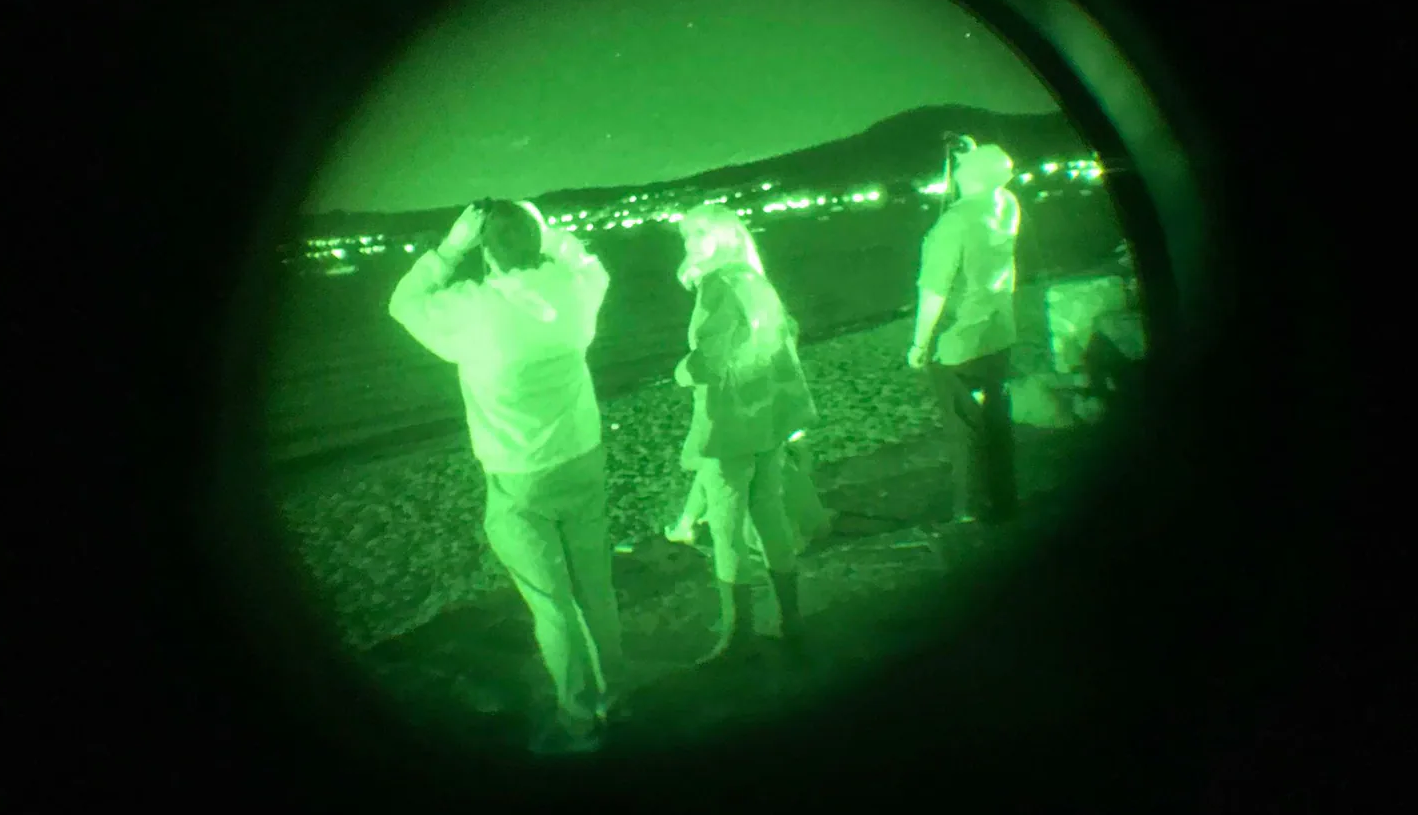 Personas mirando el cielo con gafas por la noche