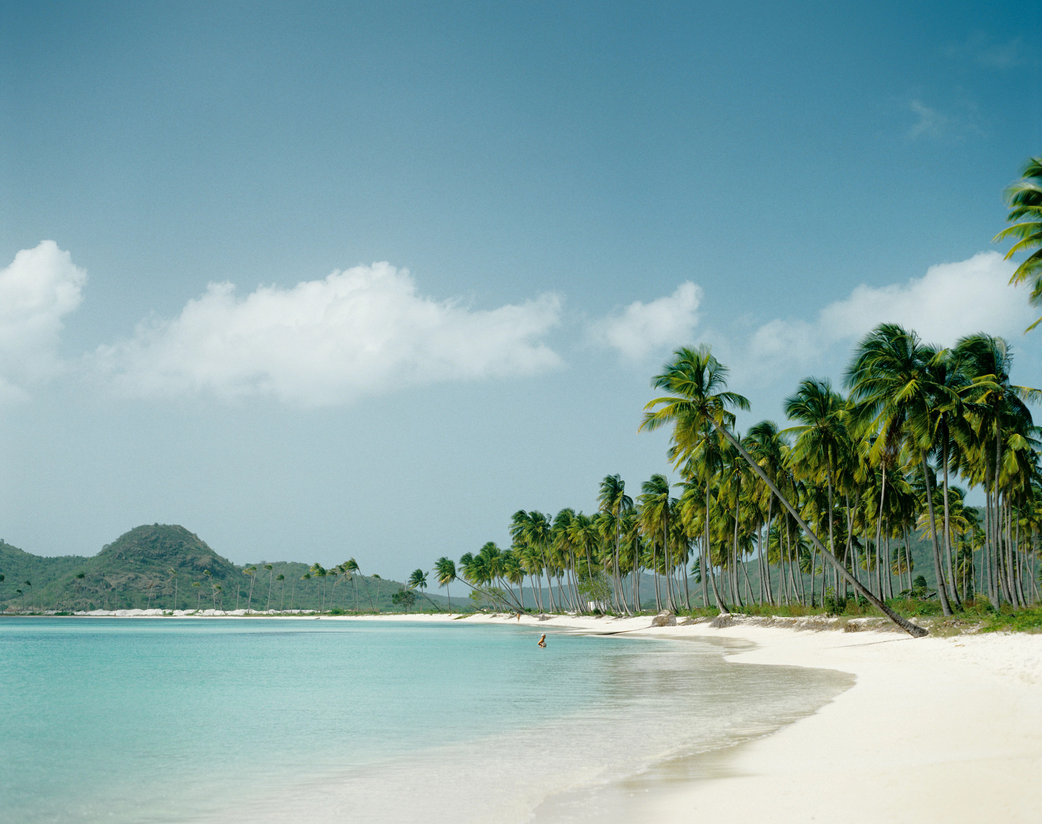 a person wading in the water off the shore of a beach