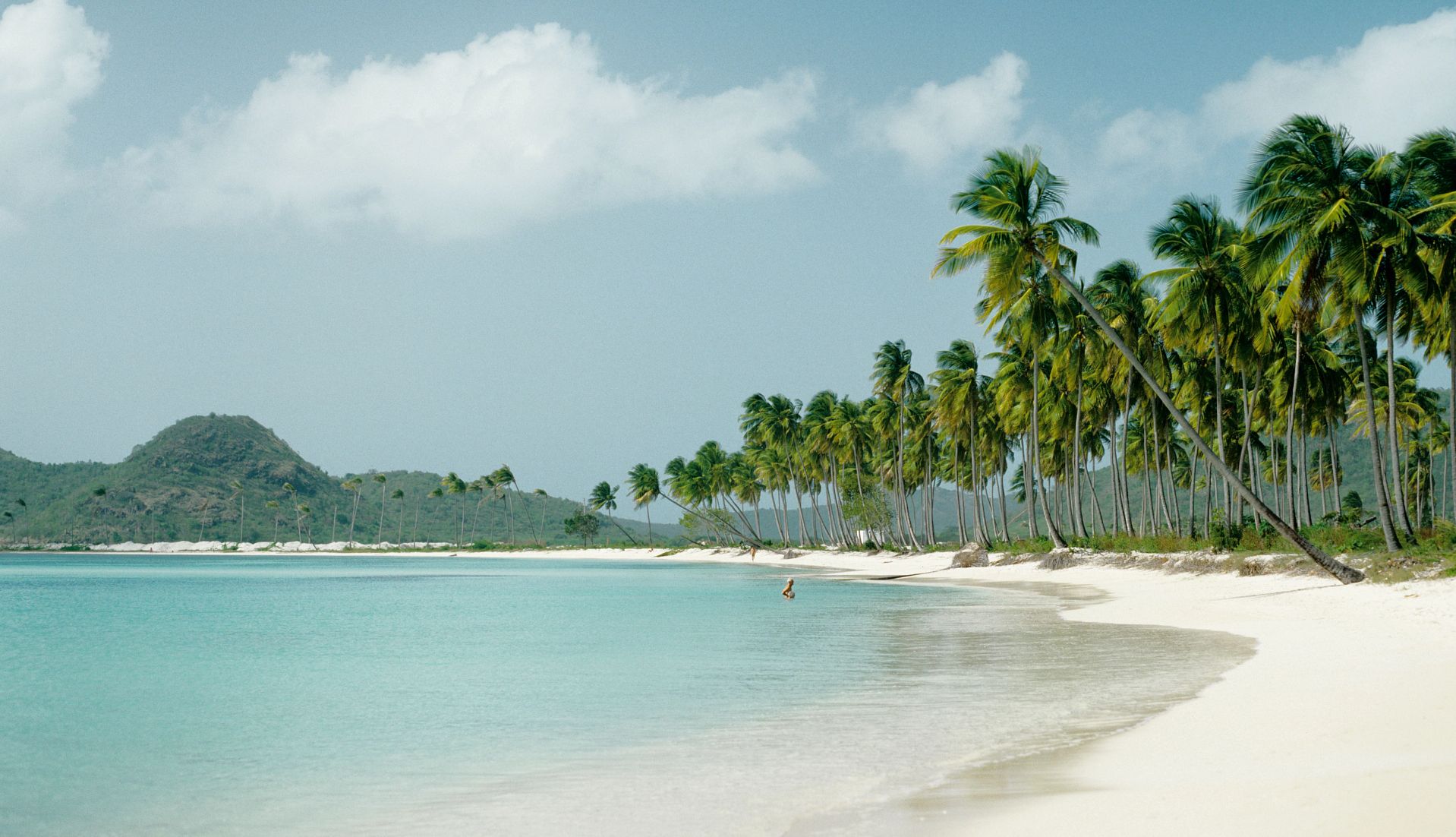 Quiet Caribbean Beaches a person wading in the water off the shore of a beach