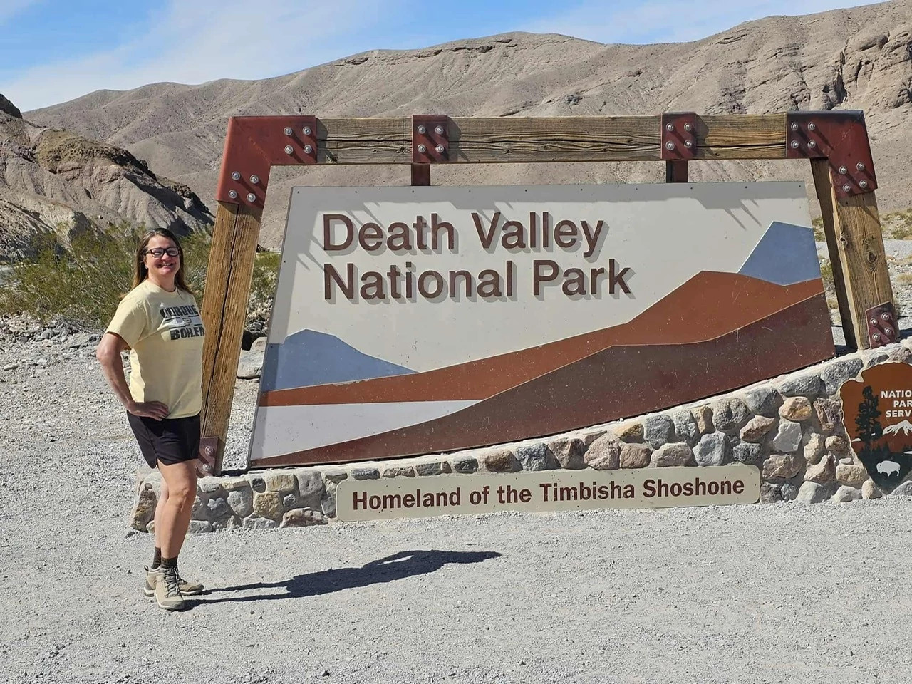 a woman standing next to Death Valley National Park signage