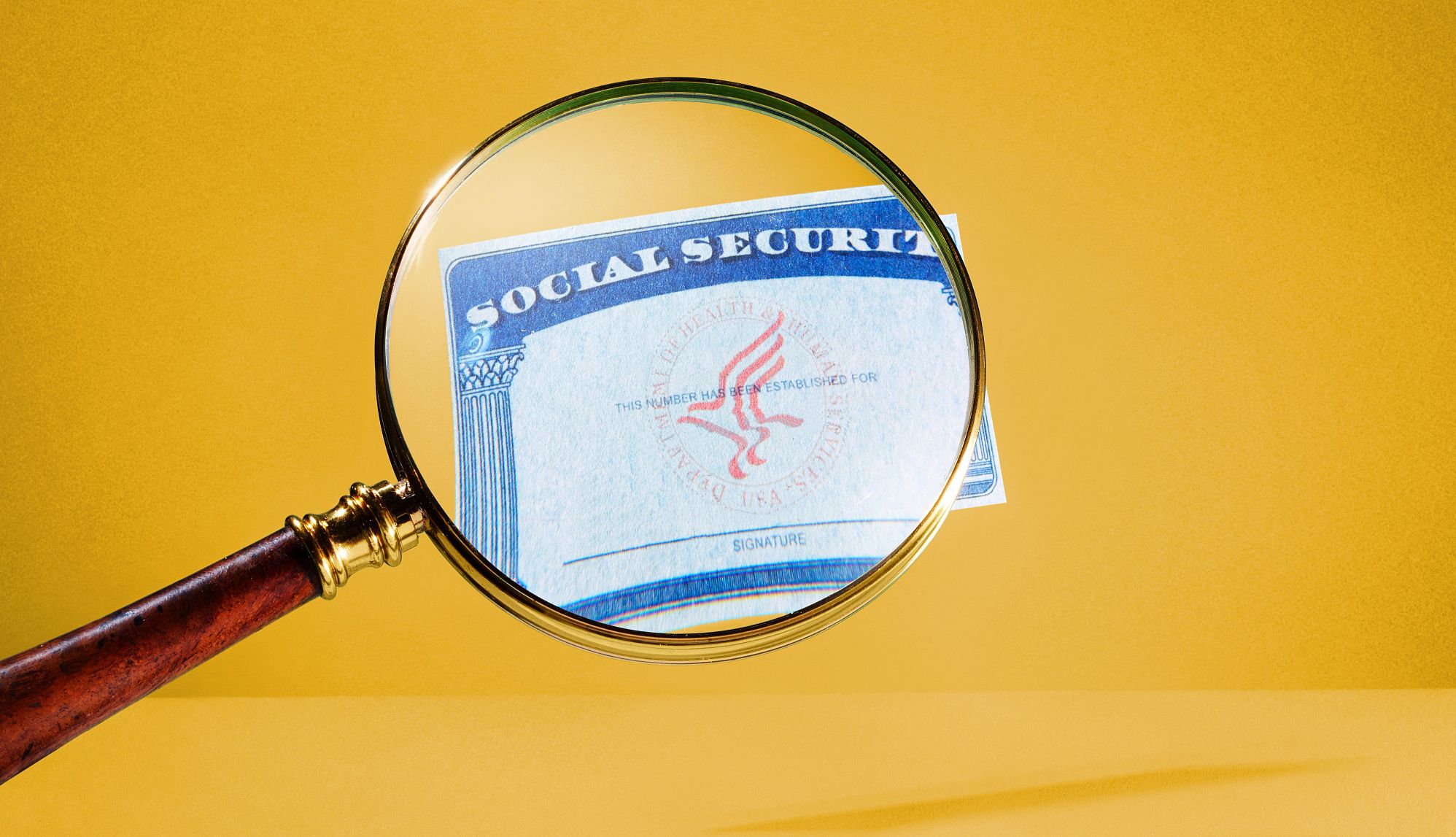 social security card under a magnifying glass on a gold background