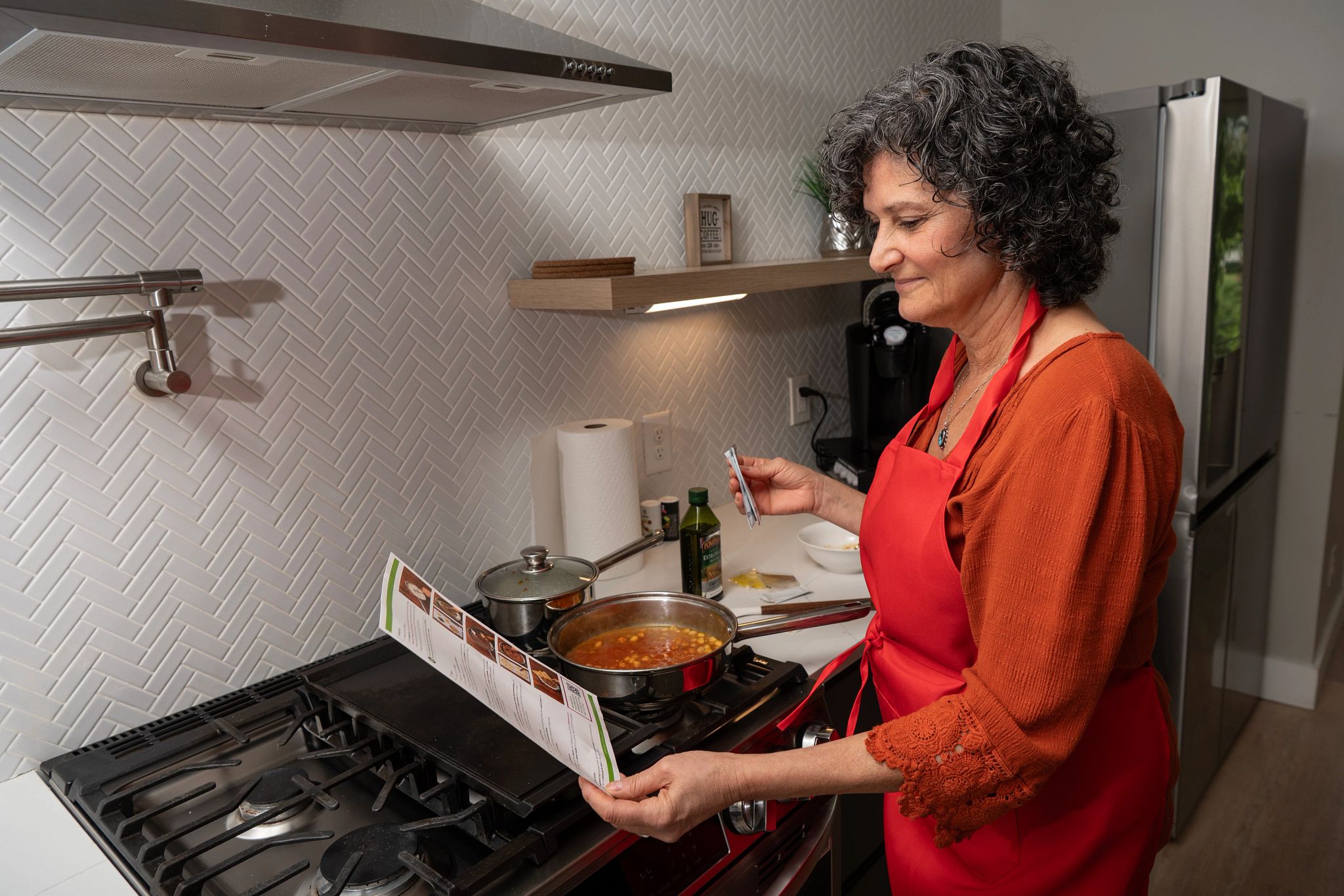 An older adult tester reading the recipe card of her Green Chef meal.
