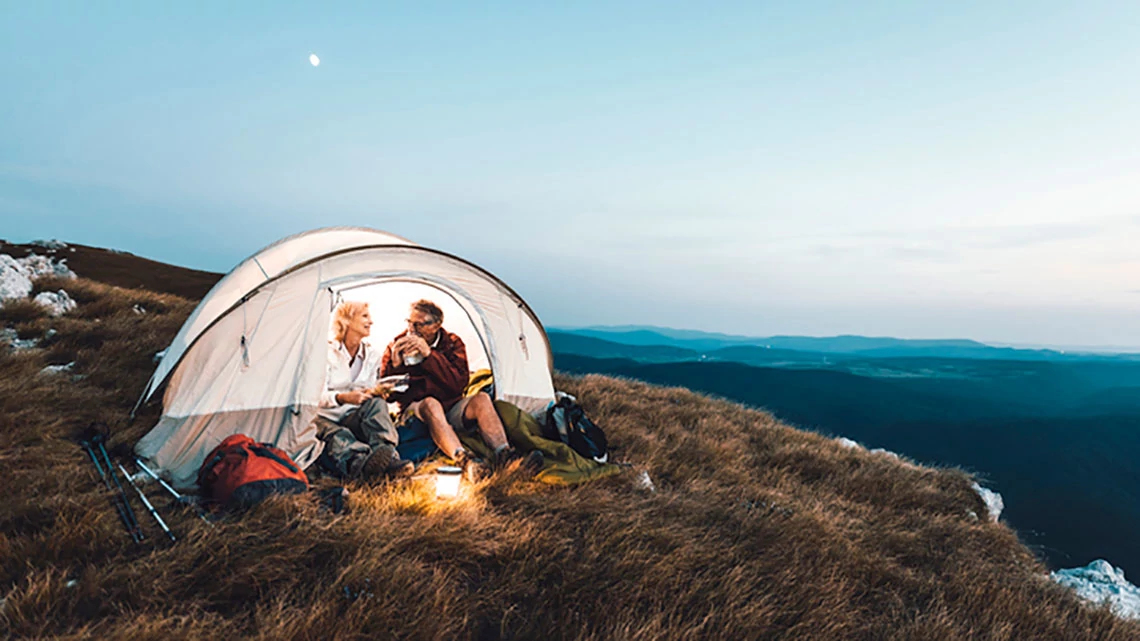 AARP Travel Couple tent mountainside eating