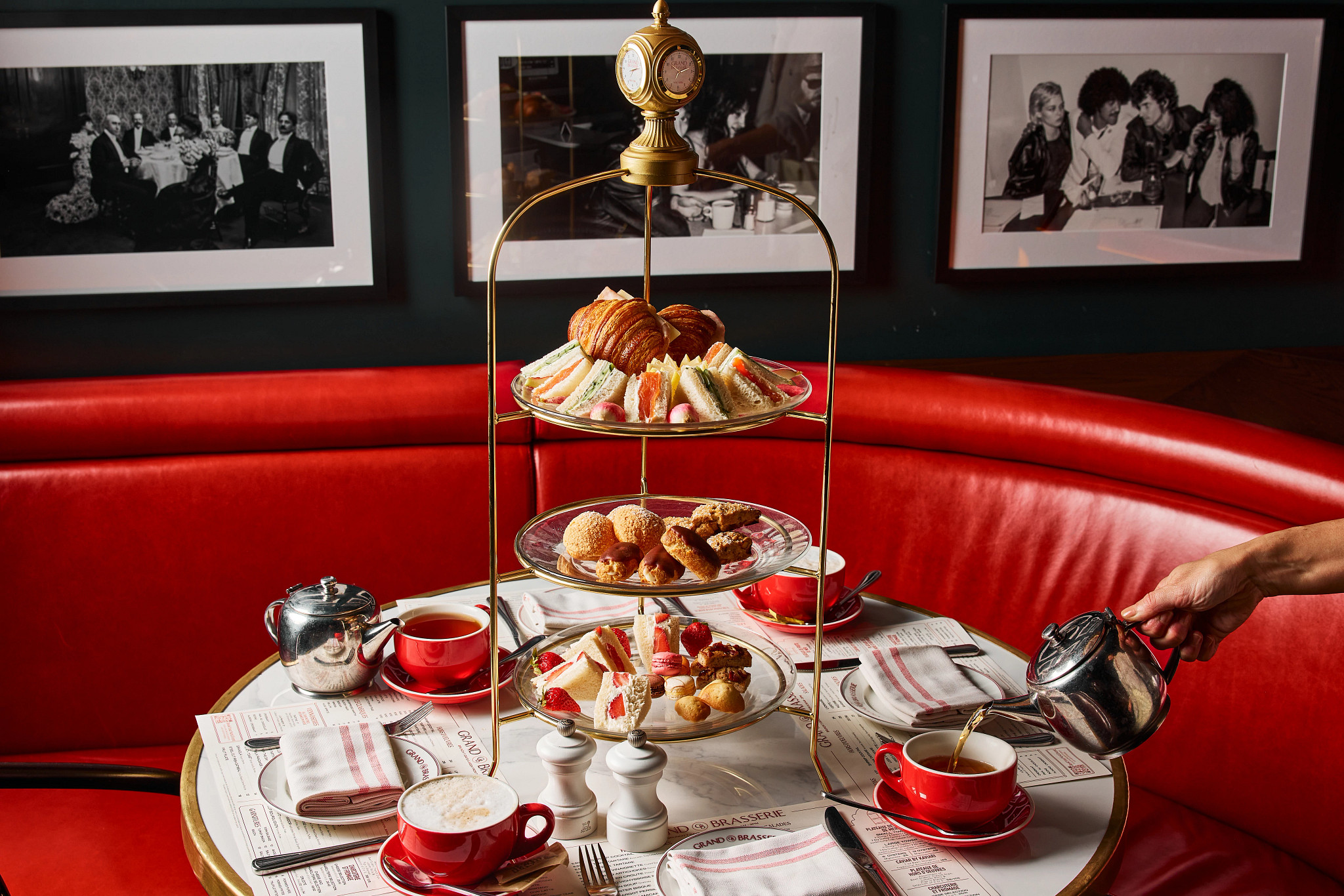 tea cups on a table along with a three tiered serving plater with desserts 