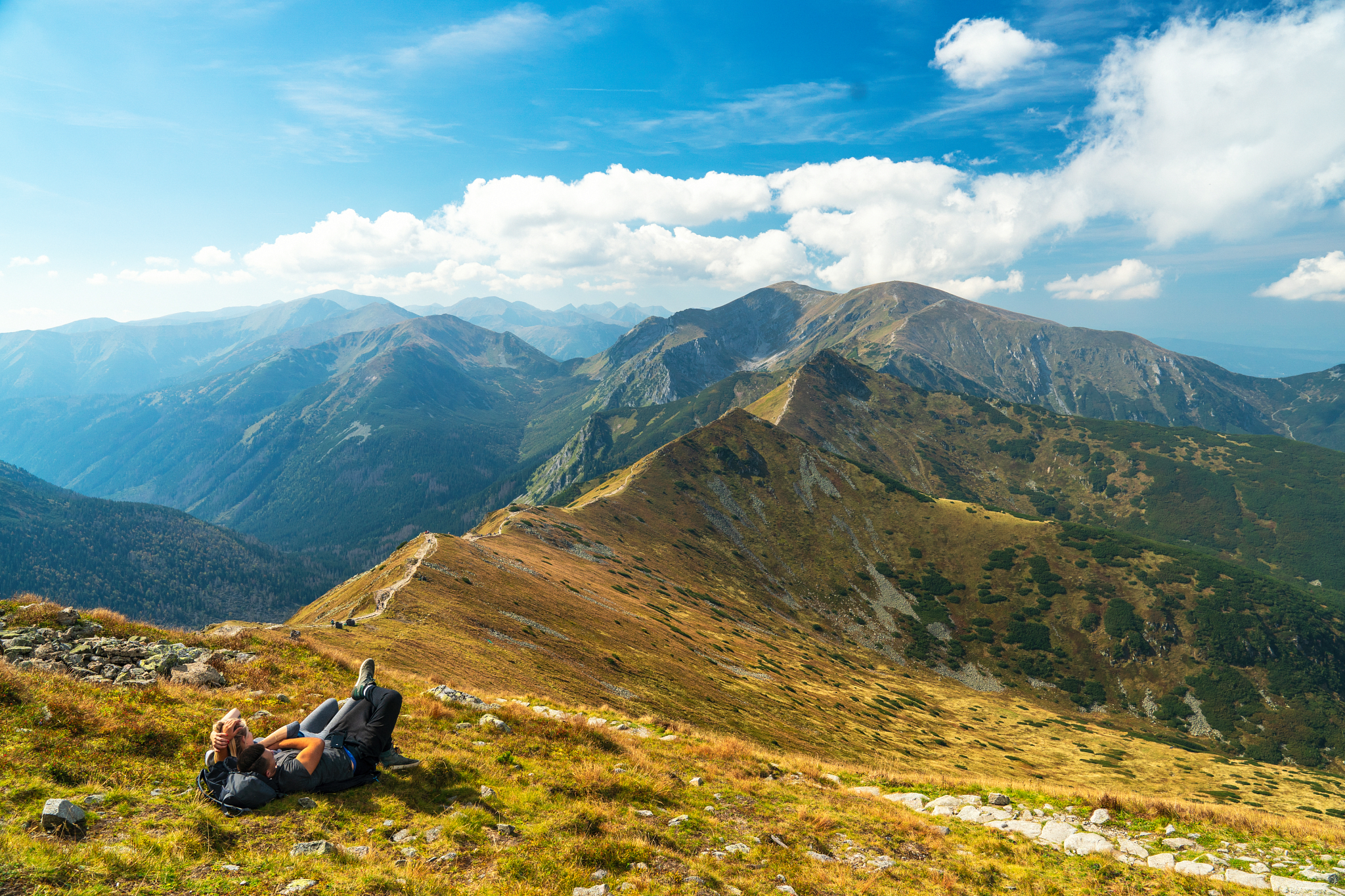a man laying on grass observing Tatra Mountains