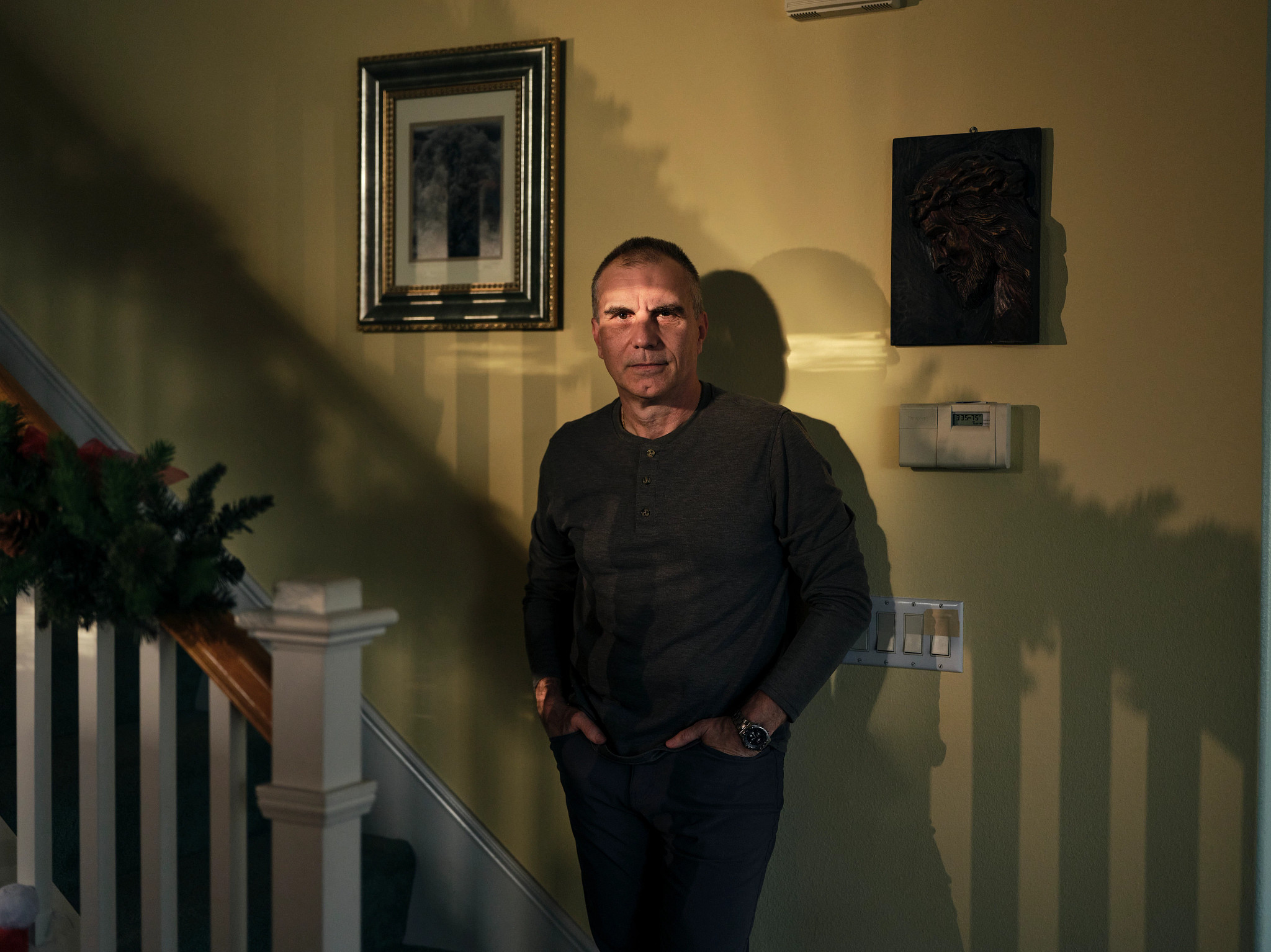 a man stands in shadows at the bottom of a staircase