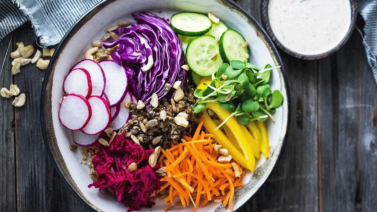 A close-up view of a rainbow buddha bowl with cashew tahini sauce in a bowl