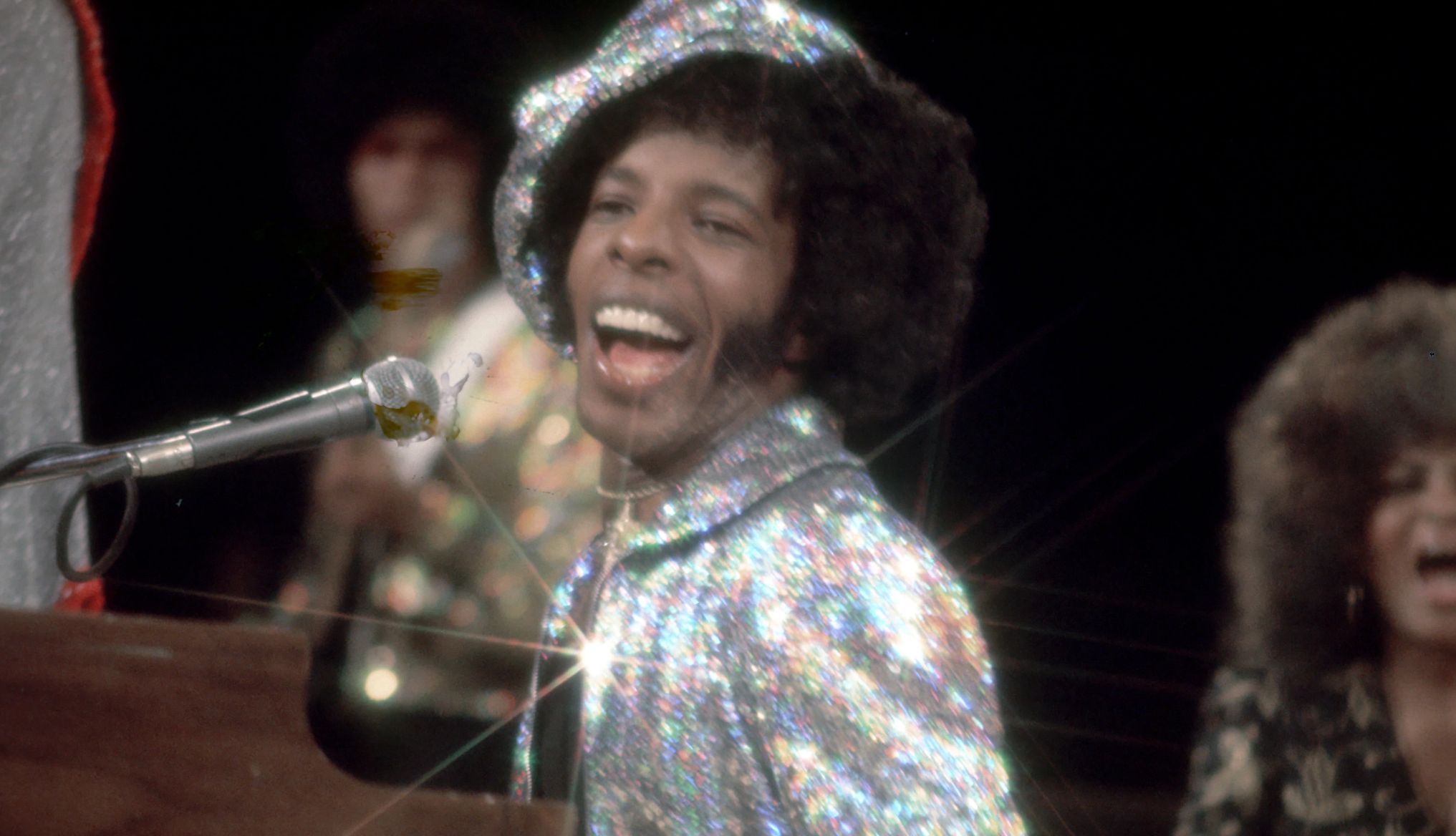 Sly Stone Dies at 82 Sly Stone performing onstage in a sparkling hat and jacket