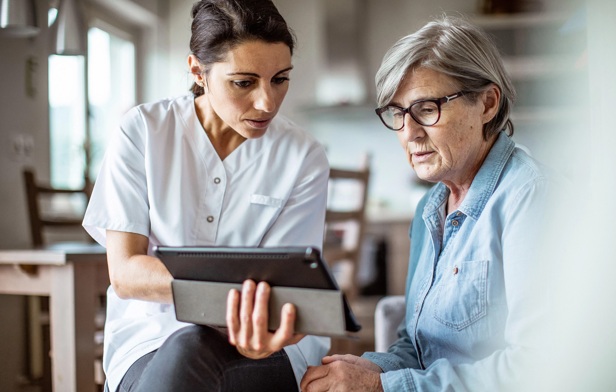 Nurse visiting a patient and reviewing her charts