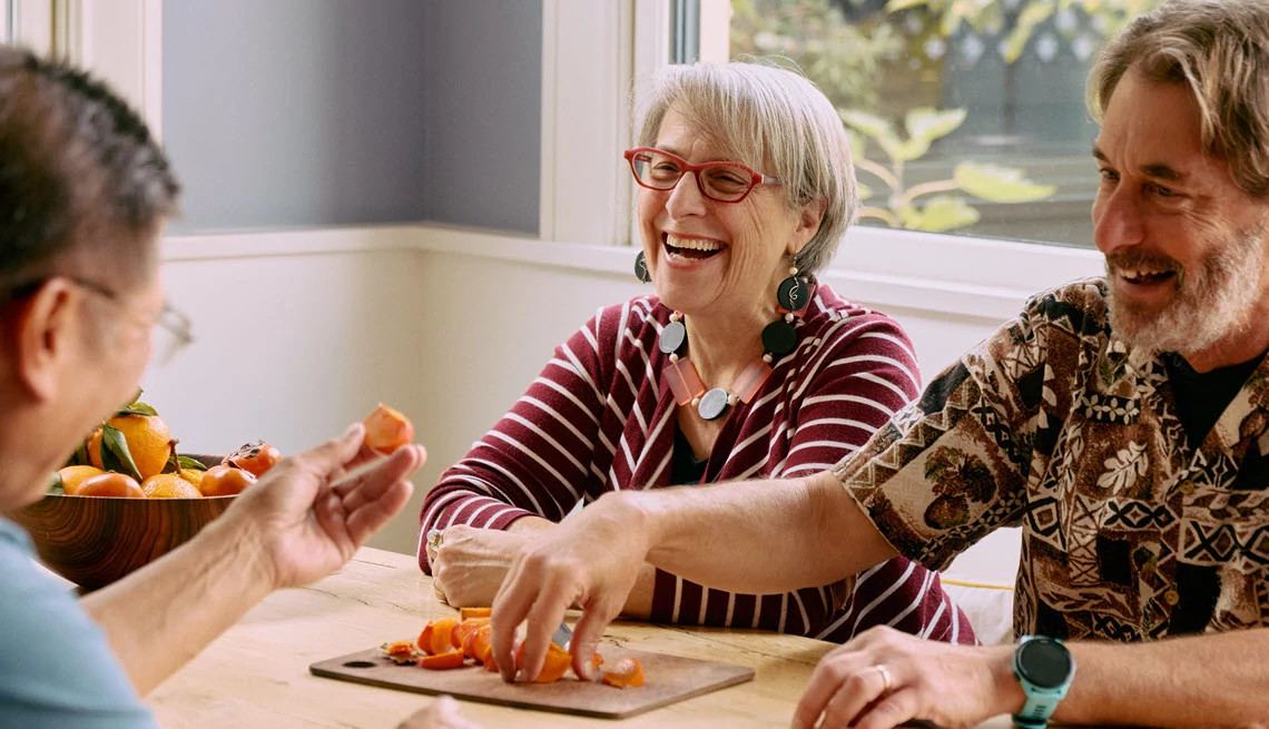 Group of mature adults sitting together have a snack at their kitchen table