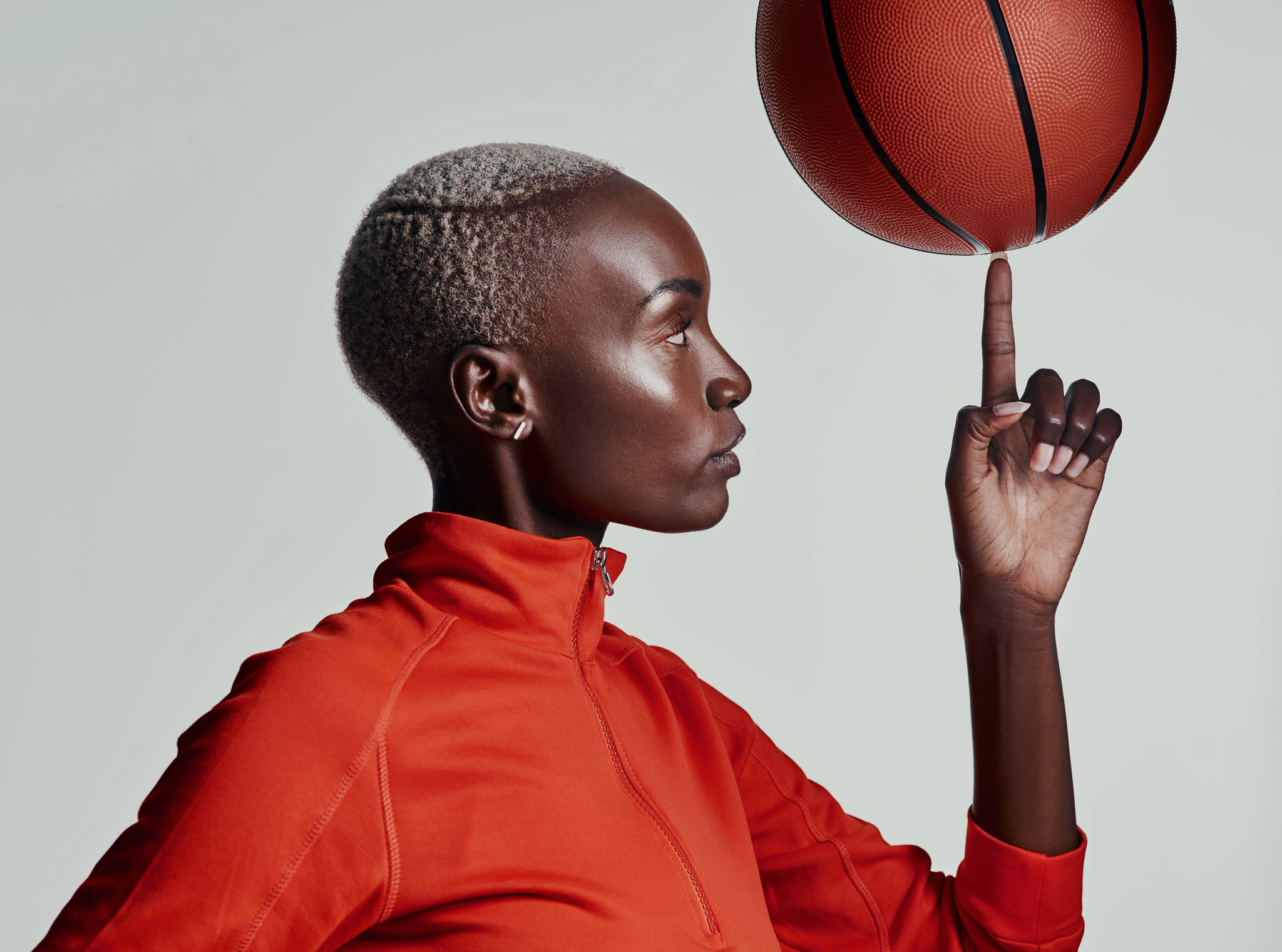 Studio shot of an attractive young woman playing basketball against a grey background