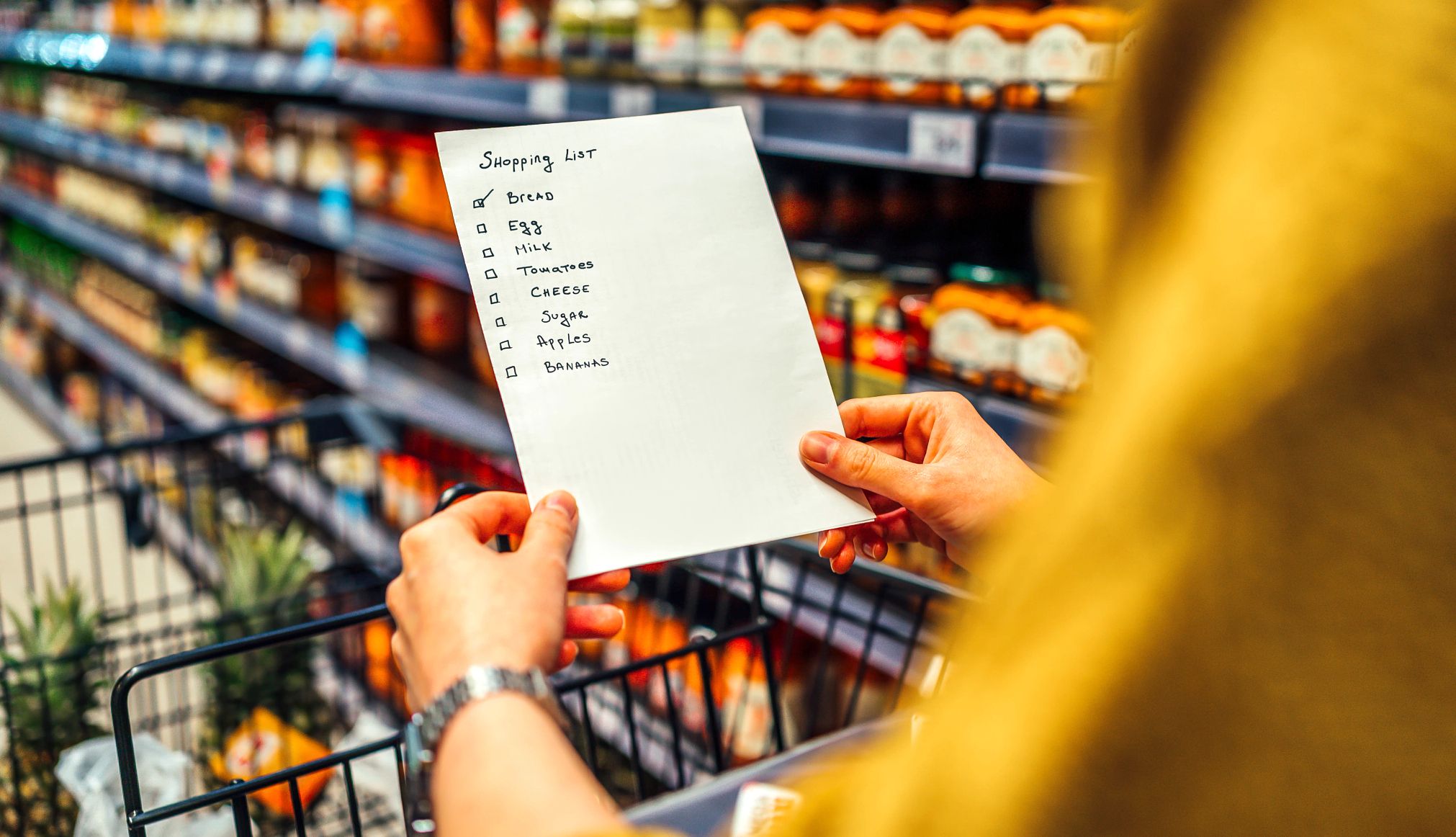 Trampas de gasto en el supermercado Lista de compras en las manos de una mujer en el supermercado