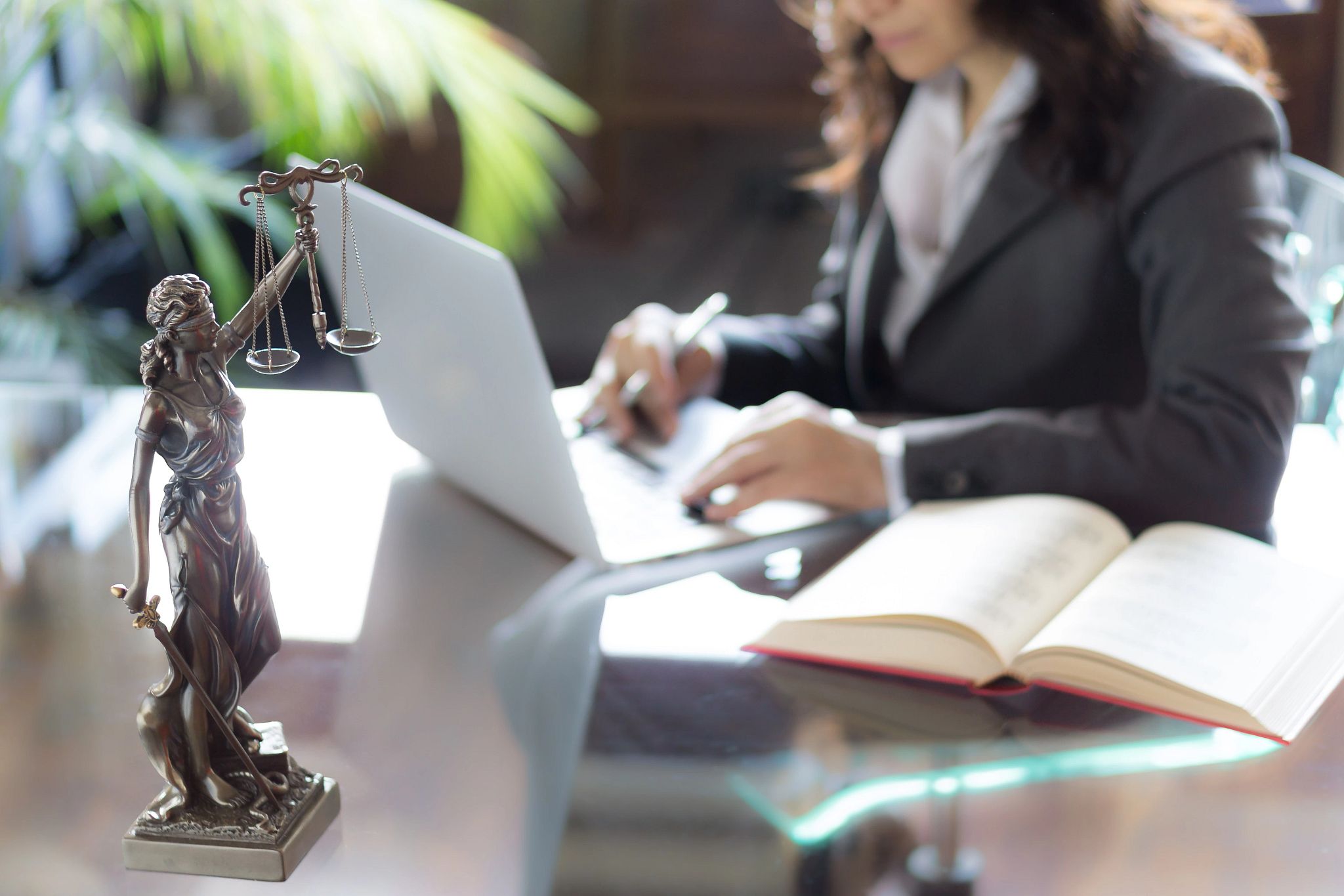 Woman lawyer typing on computer, justice scales in front Woman lawyer typing on computer, justice scales in front