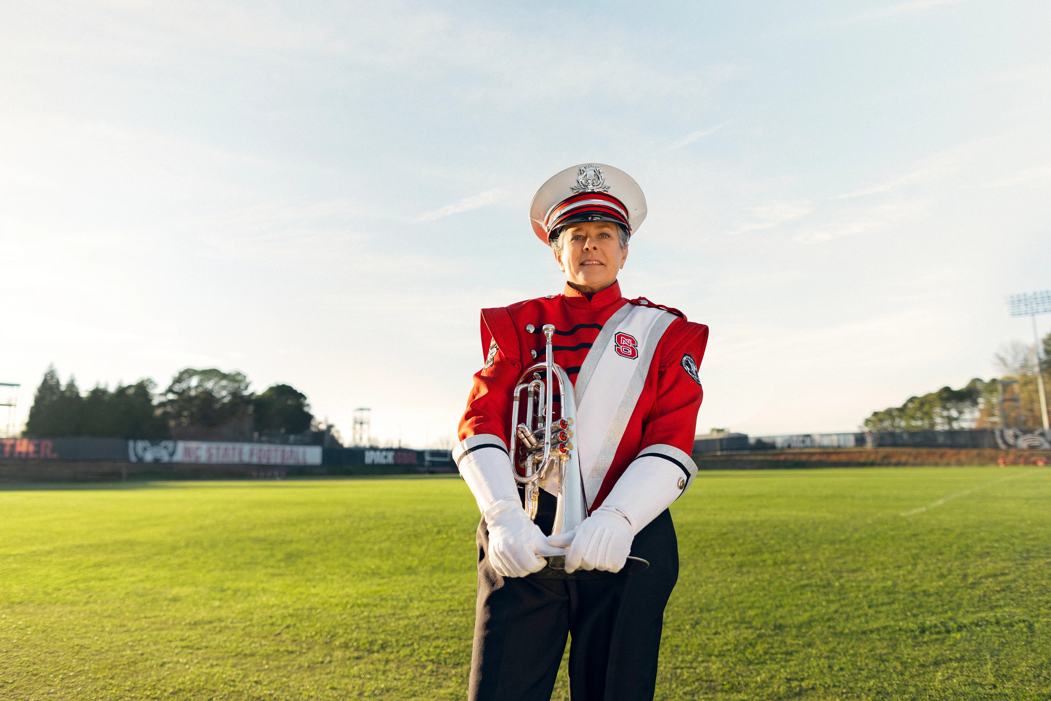 Lois Roegge stands on an empty football field in her marching band uniform holding her Mellophone