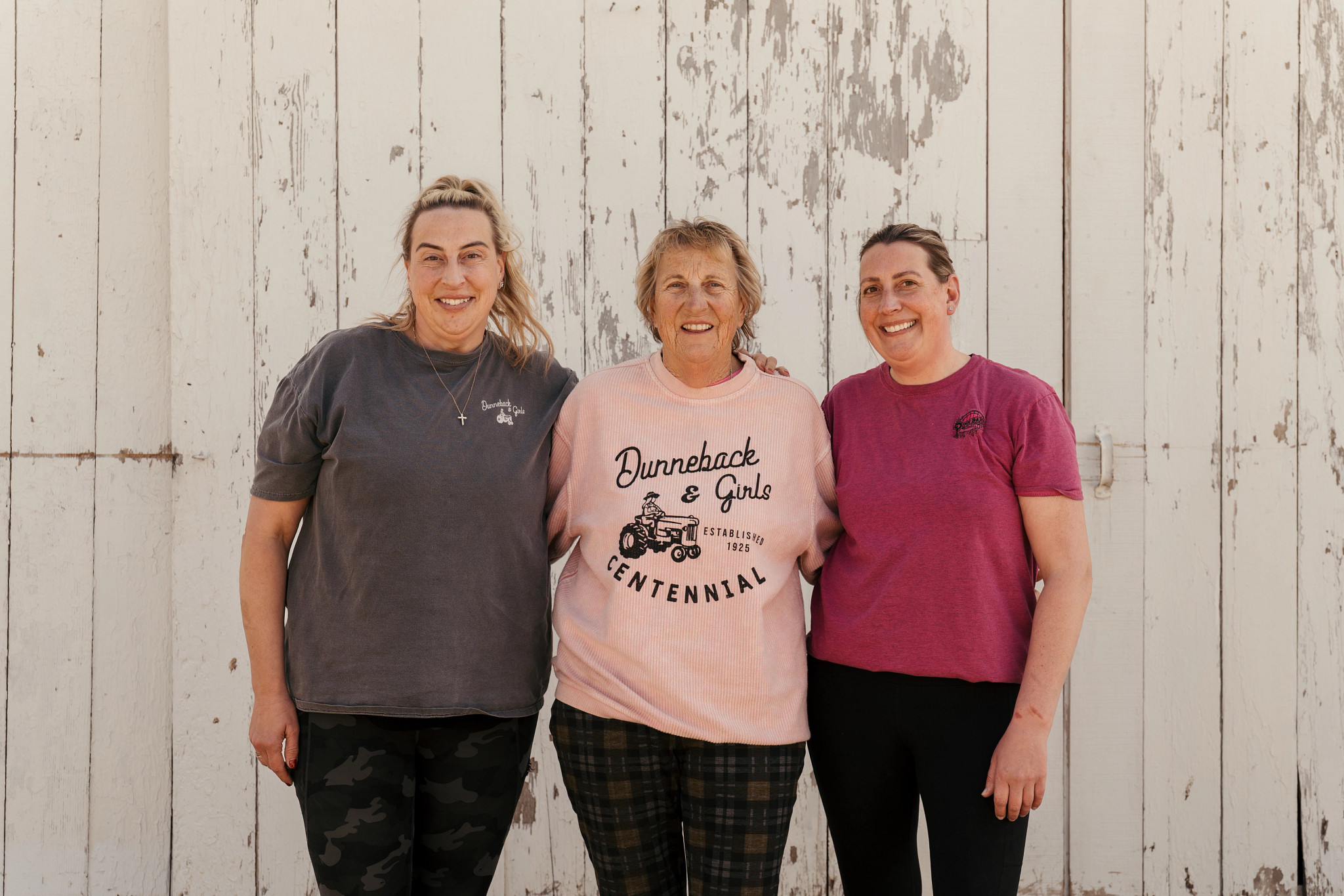 Stephanie Ginsberg, Suanne Shoemaker and Sara Stoddard standing together outdoors in front of a rustic wooden barn
