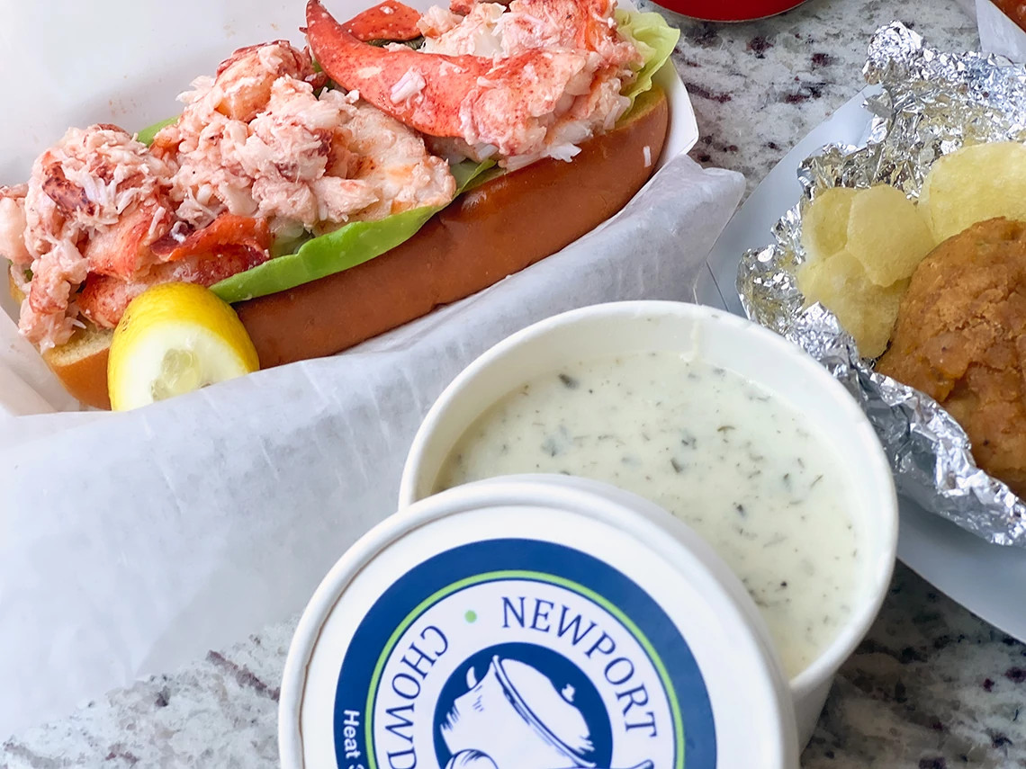 a bowl of clam chowder next to lobster meat and other food
