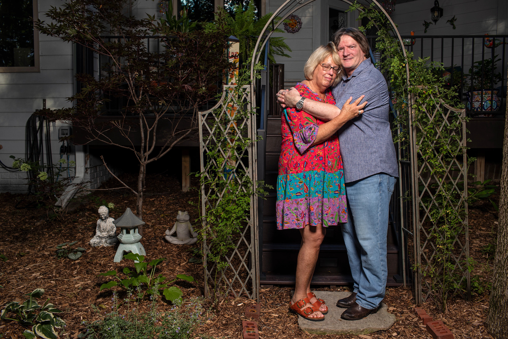 Marty Parrish and Peggy Huppert embrace under an arch in their garden