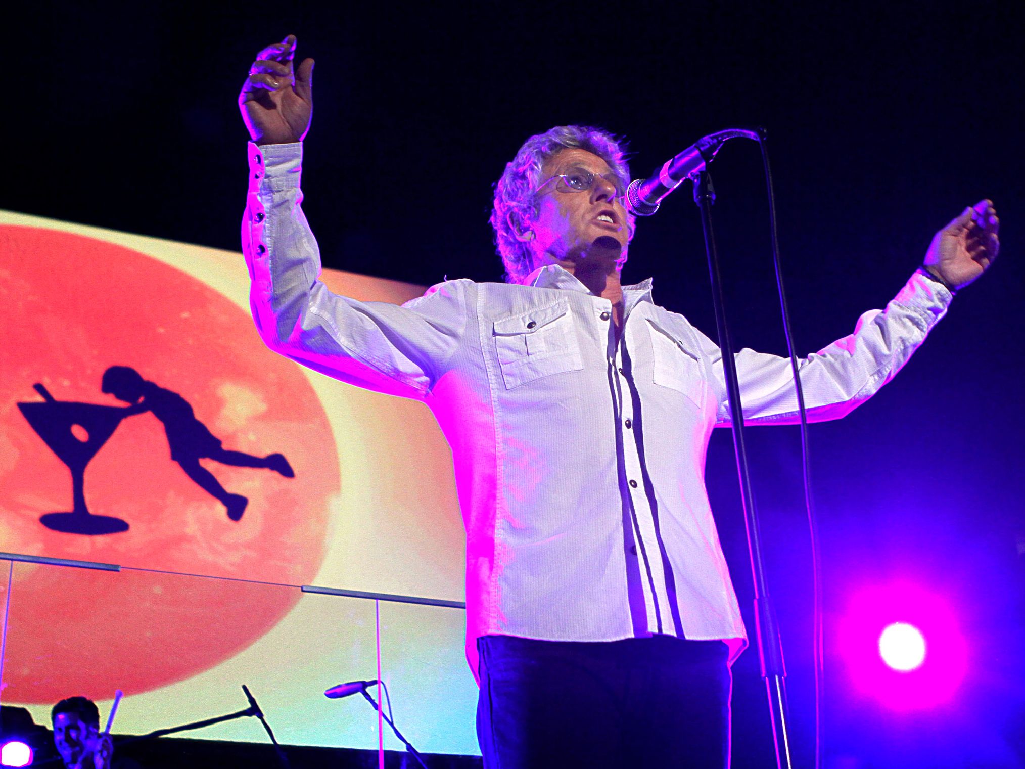 Roger Daltrey performing rock opera Tommy Roger Daltrey singing into a microphone during a performance of the rock opera Tommy in Boston