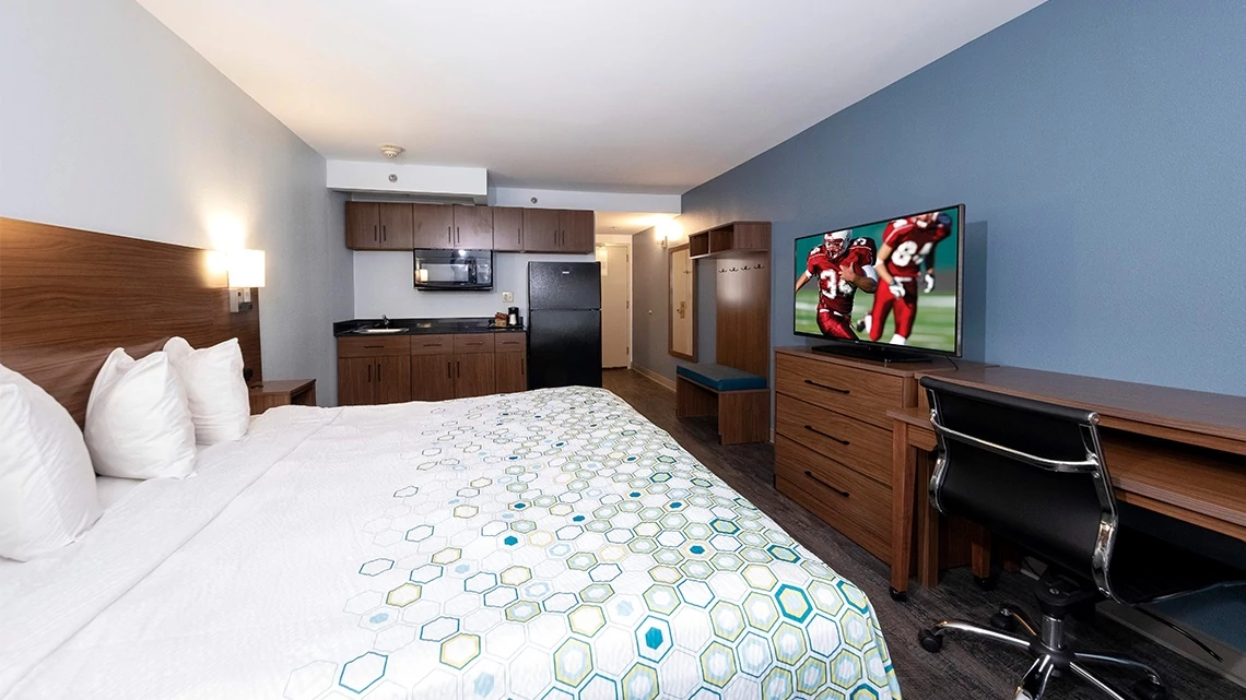 HomeTowne Studios by Red Roof Room bed blue wall kitchenette
