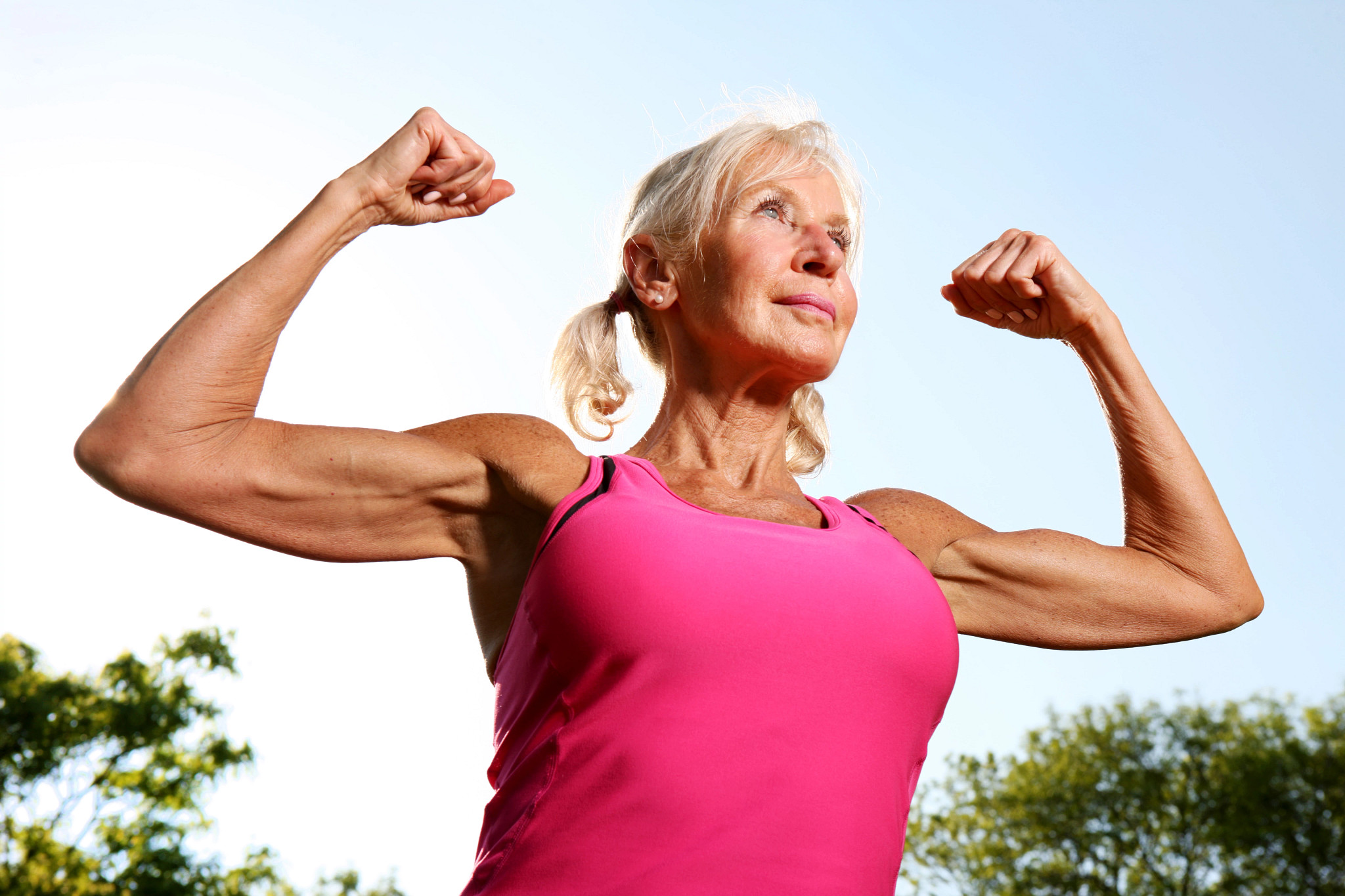 Older woman flexes her bicep muscles along the Chicago, IL, lakefront