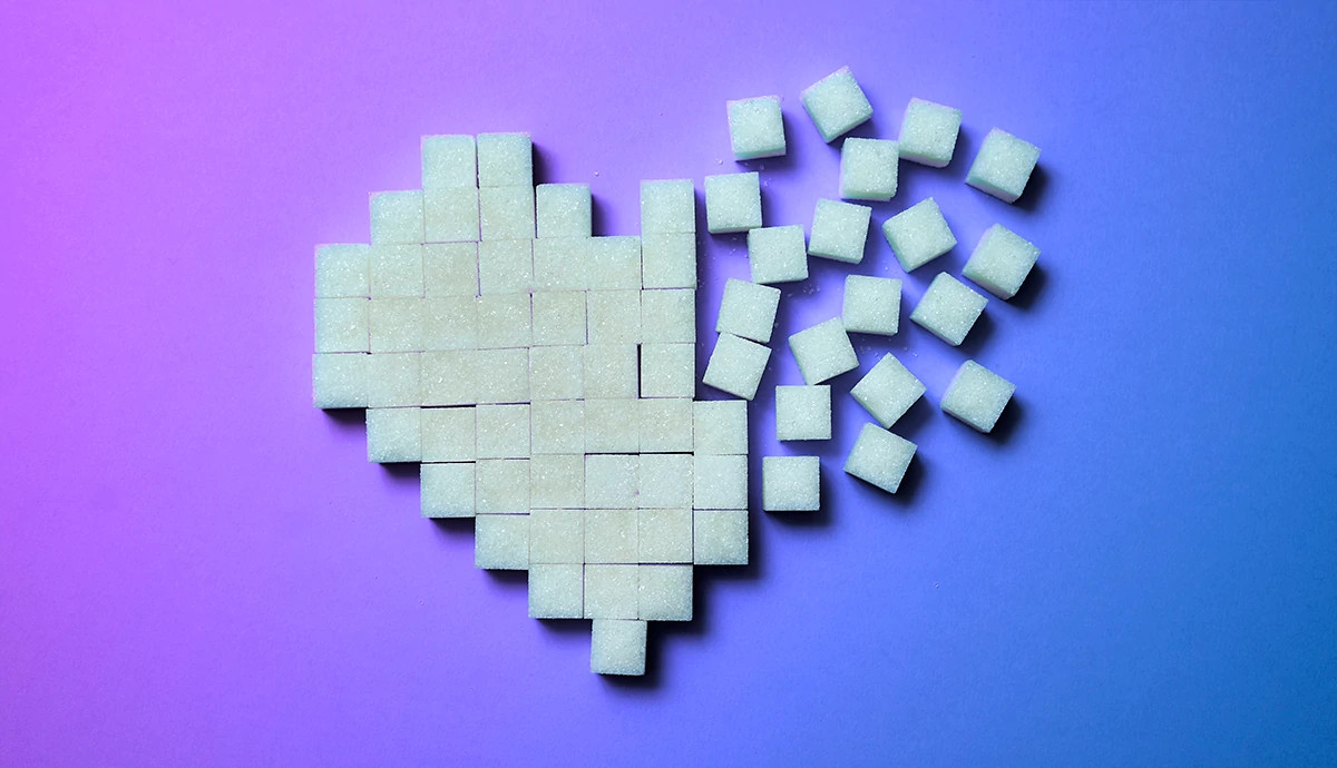 Sugar cubes arranged in heart shape on blue background