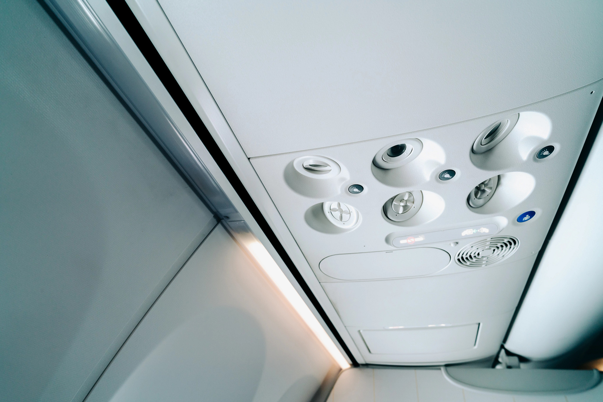 Close-up of an airplane overhead panel with air vents and lighting controls