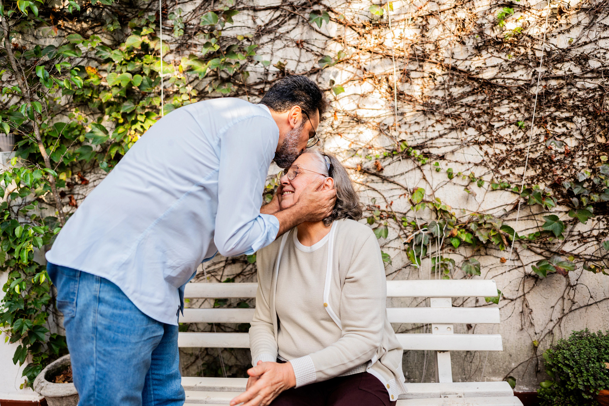 Son kissing his mother forehead at home