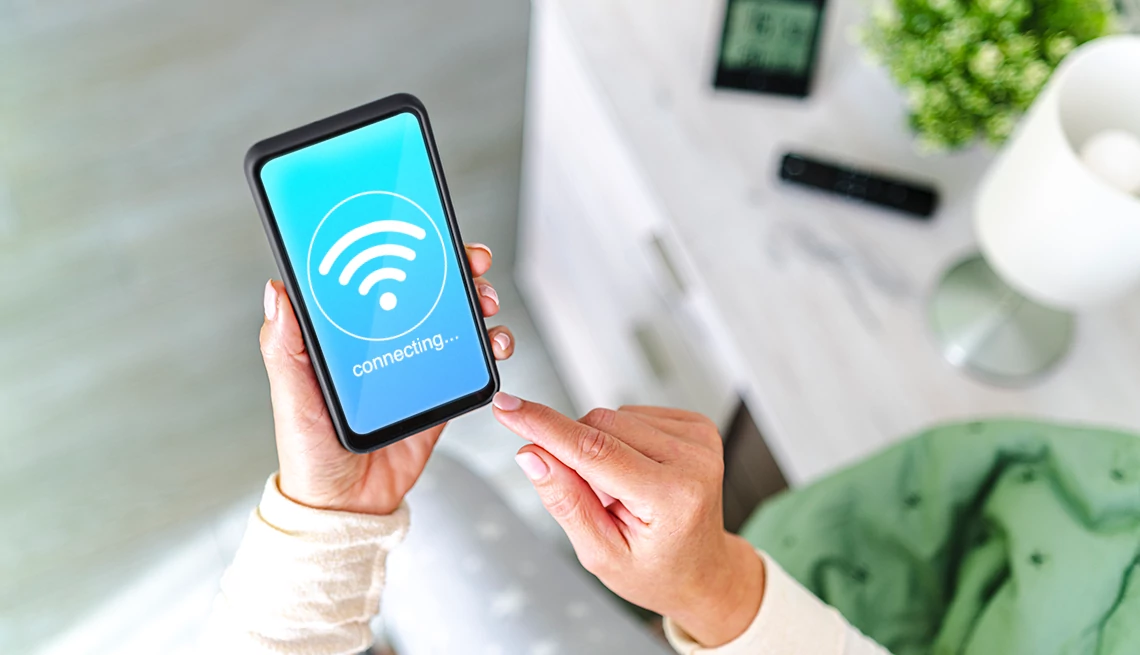 Why You Should Connect Your Mobile Phone to Your Home’s Wi-Fi a person holding a smartphone with a wifi signal on the screen