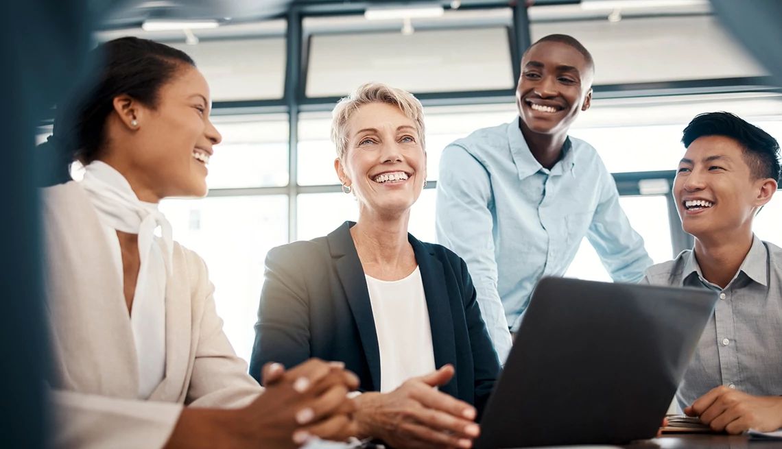 Help organizations learn about best practices for promoting workplace health and well-being Four smiling people working together on a laptop in an office setting