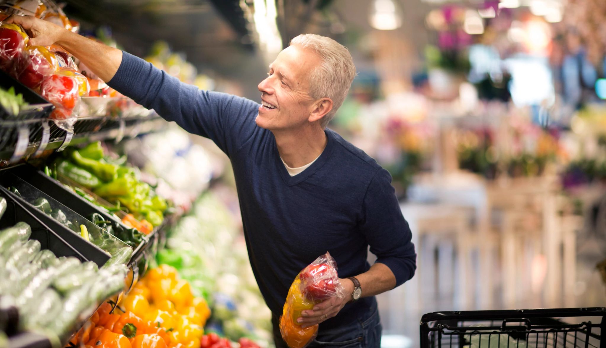 Eating fruits and veggies can help to lower blood pressure. man shopping for healthy food at the grocery store
