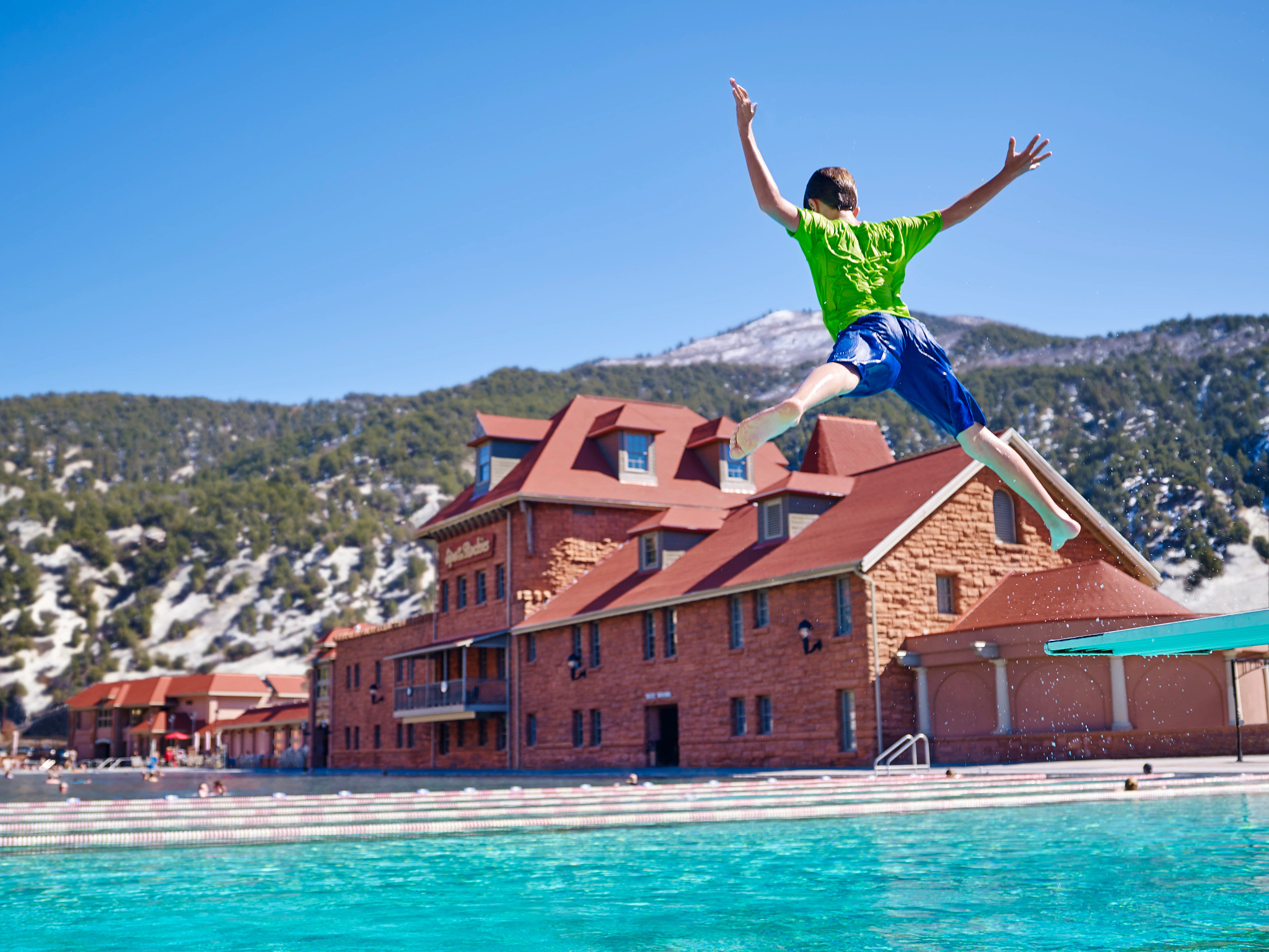a boy jumps into a pool at Glenwood Hot Springs Resort 